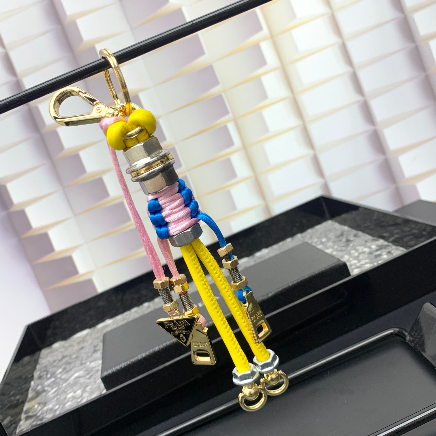 新款🌟这款钥匙扣呈现 Saffiano 牛皮革手工编织富有辨识度的十字纹理，饰有标志性的涂珐琅金属徽标。