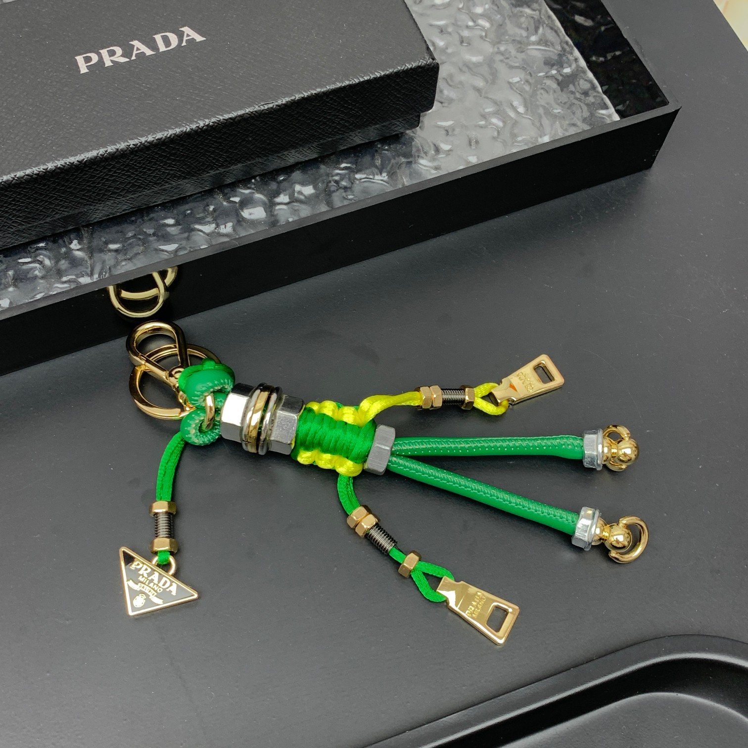 新款🌟这款钥匙扣呈现 Saffiano 牛皮革手工编织富有辨识度的十字纹理，饰有标志性的涂珐琅金属徽标。