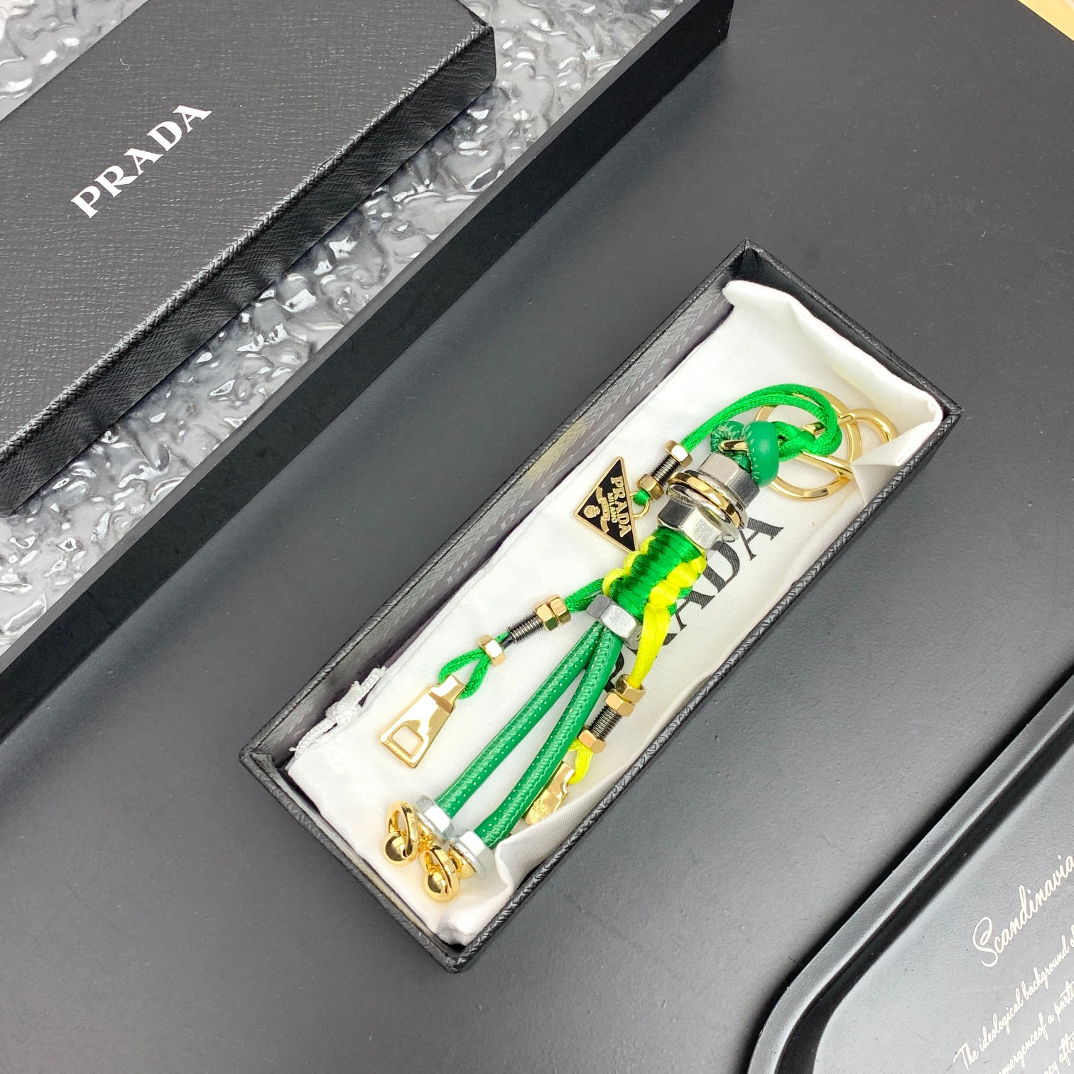 新款🌟这款钥匙扣呈现 Saffiano 牛皮革手工编织富有辨识度的十字纹理，饰有标志性的涂珐琅金属徽标。