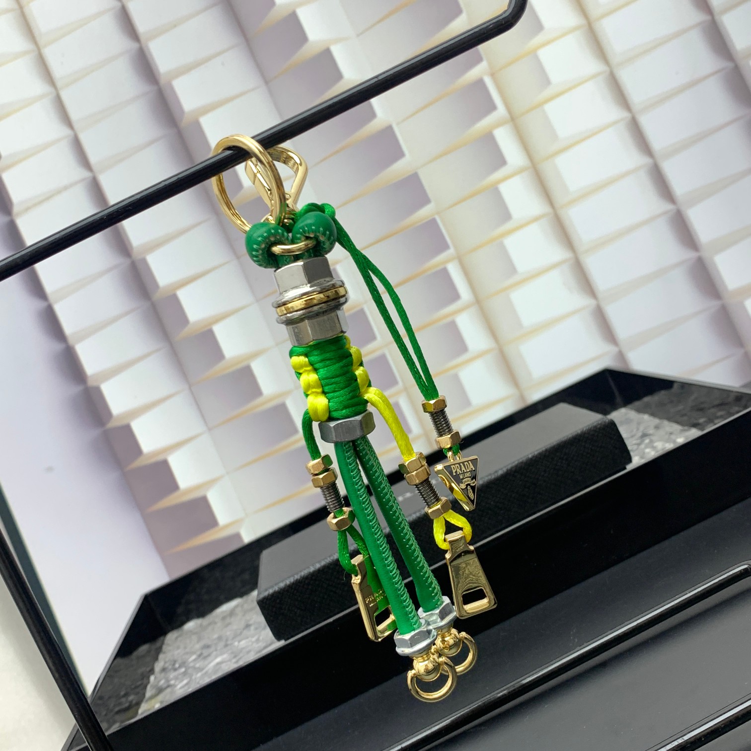 新款🌟这款钥匙扣呈现 Saffiano 牛皮革手工编织富有辨识度的十字纹理，饰有标志性的涂珐琅金属徽标。