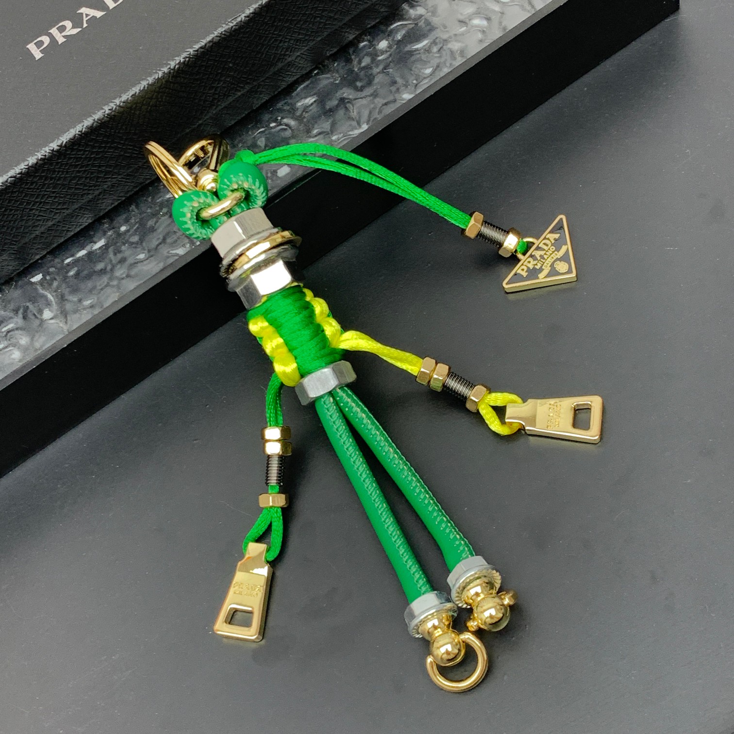 新款🌟这款钥匙扣呈现 Saffiano 牛皮革手工编织富有辨识度的十字纹理，饰有标志性的涂珐琅金属徽标。