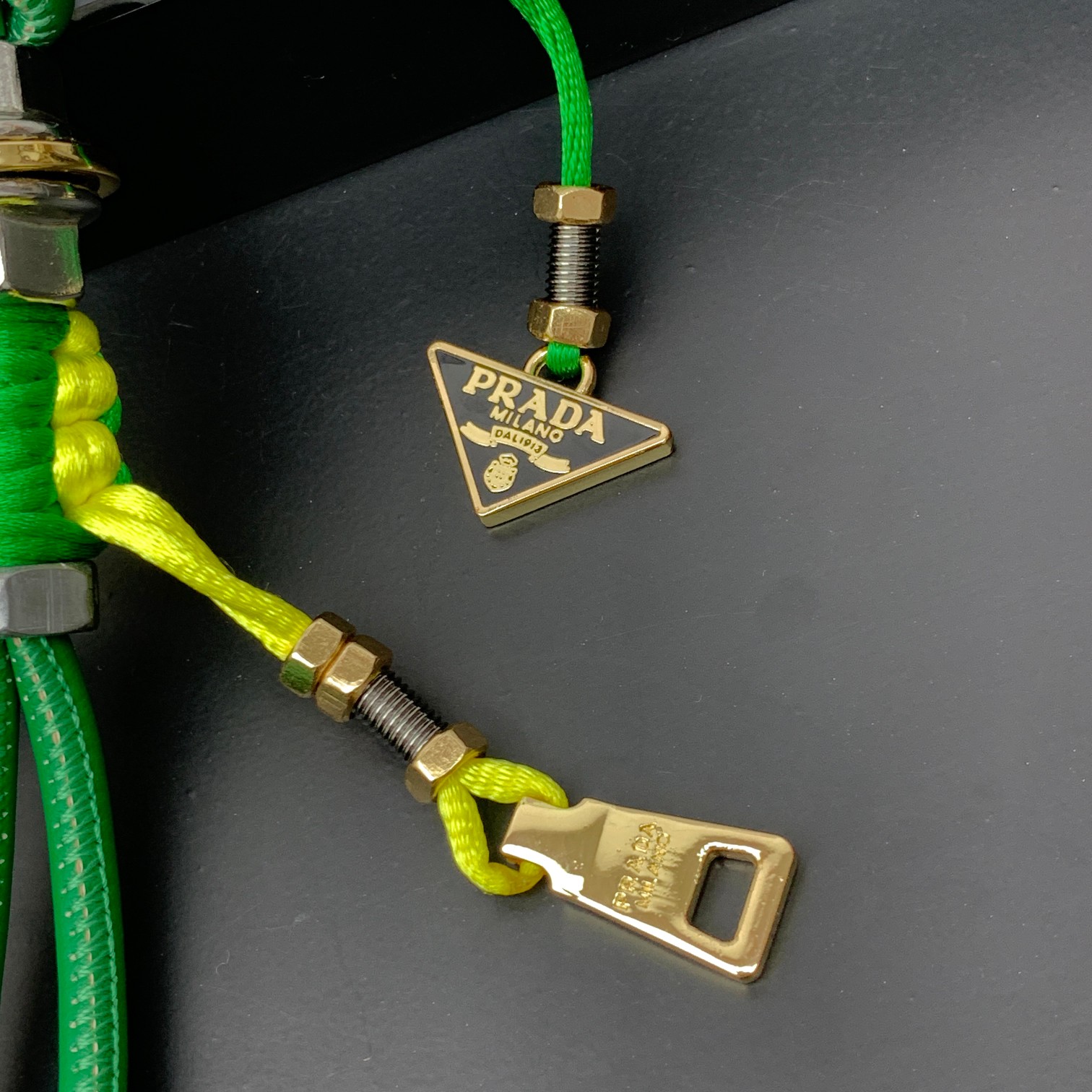 新款🌟这款钥匙扣呈现 Saffiano 牛皮革手工编织富有辨识度的十字纹理，饰有标志性的涂珐琅金属徽标。