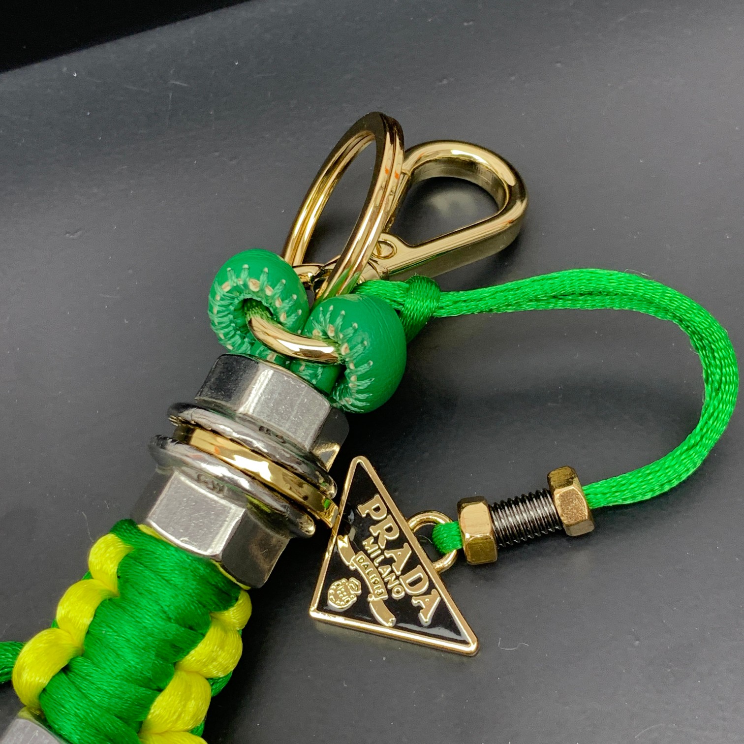 新款🌟这款钥匙扣呈现 Saffiano 牛皮革手工编织富有辨识度的十字纹理，饰有标志性的涂珐琅金属徽标。