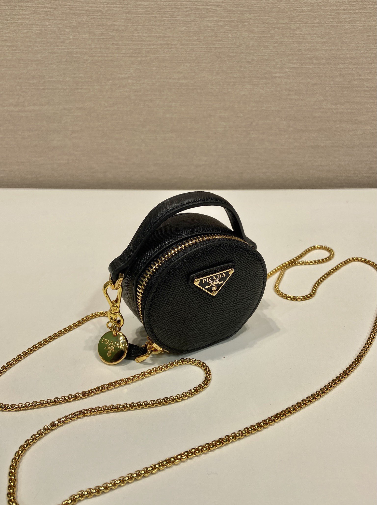 💰480🎉十字纹小圆包🎉1NR023🎉🎉
这款圆形迷你小包展现出现代而精致的廓形，采用十字纹牛皮，饰有闪闪发光的金属五金配件，搭配优雅的可拆式链条肩带，太可爱了😍上身效果非常吸眼，可仙可酷，难道你不心动😗😗，美妞们，赶紧入手吧，太美太可爱了😋😋
长8x高8x底3.5cm🎉🎉🎉👏👏👏