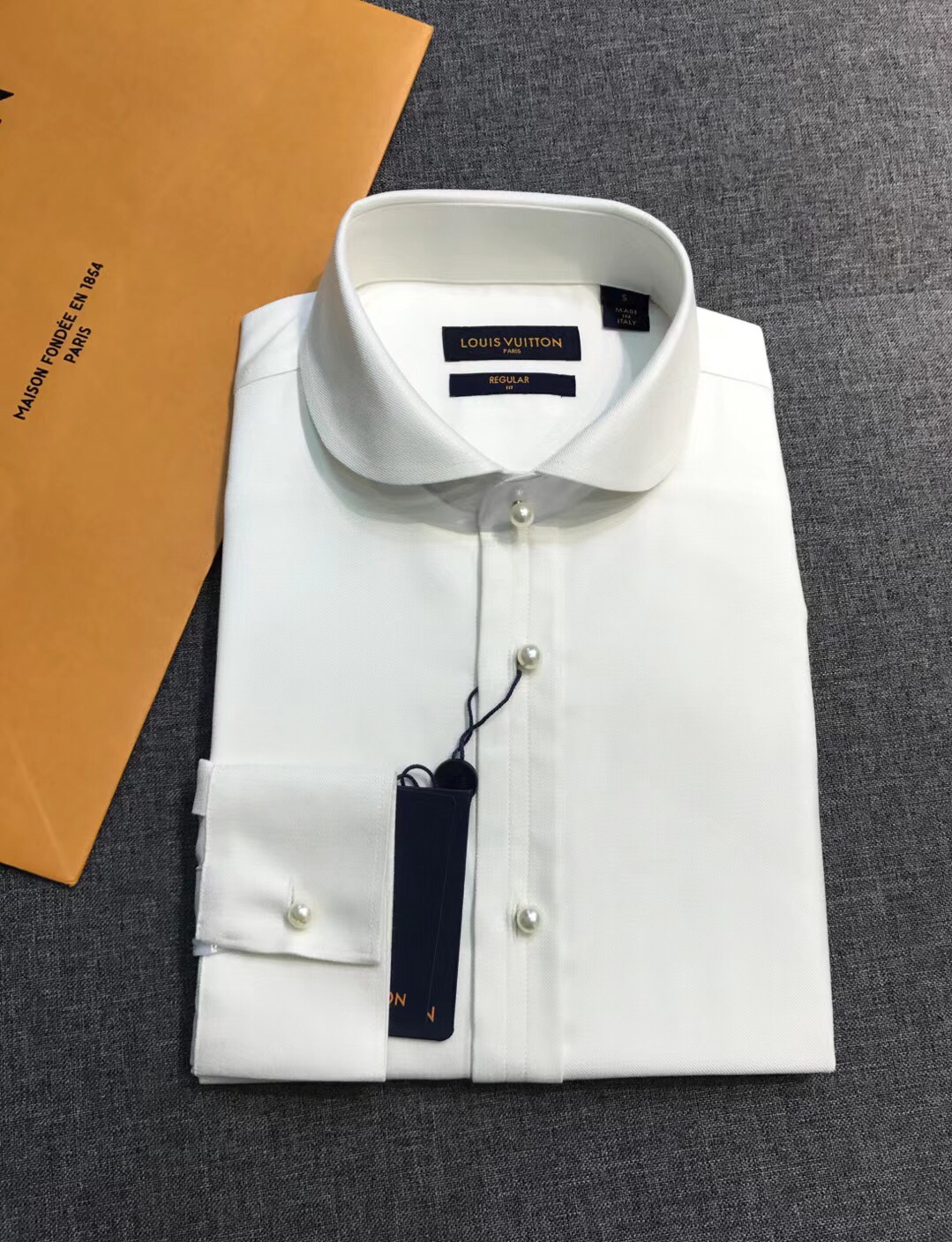 NO:607092,[New Product] - Vden family men's high-end fashion model mulberry silk blended pearl button long-sleeved shirt, a heavy-duty high-end product, another high-end luxury platinum-level item, the official early spring 25 series, pure appearance!  This is a high-end, luxurious and platinum-level shirt. The overall design style has a strong Fei Dong label. The appointment of creative director Pharrell Williams has injected new elements. The body of the shirt uses the Marque L. Vuitton Déposée elements, cleverly embellished on the back collar. The injection of pearl-shaped buttons enhances the overall visual beauty. It is high-end, fashionable and gorgeous, and has a profound fashion charm!  Customers select fabrics from Swiss ALUMO company. The fabric is made of combed ultra-fine GIZA45 grade poplin Egyptian cotton, high count double worsted and custom-woven, blended with a certain proportion of silkworm material, which is quite noble and luxurious.  , the texture and comfort of the fabric are at its peak, the skin-friendliness and breathability are excellent, and the touch is extremely delicate and skin-friendly. It is even better after being treated with the non-iron process. The fabric texture is luxurious, with its own elastic drape, casual and full of relaxation!  The details are also very outstanding, with a unique and elegant rounded collar design, tight stitching, exquisite handwork on the buttons, first-class tailoring, and exclusive sophisticated cutting technology!  The color scheme is simple and versatile, suitable for all kinds of daily wear. The compatibility is very high, and it can be used in any occasion, whether for business commuting or outing for leisure. The upper body has a strong sense of elegance. It is a high-end item that must be included in the wardrobe!  Size S-XXL S, shoulder width 45, bust 102, sleeve length 62, clothing length 73, shirts, alexander wang19860909【新品】 -V登家族男士高端时装款桑蚕丝混纺珍珠扣长袖衬衫,重磅高端臻品,又一枚高奢品鉴白金级单品,25年早春官方系列,品相纯正！ 高端奢华且白金级的一款颜值衬衫,整体的设计风格有着强烈的菲董标签,创意总监Pharrell Williams的上任注入了全新的元素,衣身运用了典藏标识Marque L. Vuitton Déposée元素,巧妙点缀于后领处,珍珠造型钮扣的注入,为整体视觉提升了美感,高级时髦且华丽,颇具深厚的时装韵味！ 客供甄选瑞士ALUMO阿鲁姆公司面料,面料采用精梳超细的GIZA45等级府绸埃及棉,高支双股精纺定织而成,融合混纺一定比例的桑蚕材质,相当矜贵且奢侈,面料质感与舒适度达到登峰造极,亲肤性与透气性绝佳,触感极为细腻亲肤,运用免烫工艺处理后更为出色,面料肌理透着奢华感,自带弹力垂感,随性且松弛感十足！ 在细节方面亦是非常出彩,别致优雅圆角领设计,走线严丝合缝,逢扣由精湛的手工参与,剪裁一流,拥有独家精良的裁剪技术！ 配色简约百搭,符合日常各种穿搭,混搭兼容空间极高,驾驭任何场合,商务通勤及出街休闲皆可,上身儒雅气质感极强,属于衣橱必入的一款高级单品！尺码S-XXL S码 肩宽45 胸围102 袖长62 衣长73,,shirts,alexander wang,Men's clothing