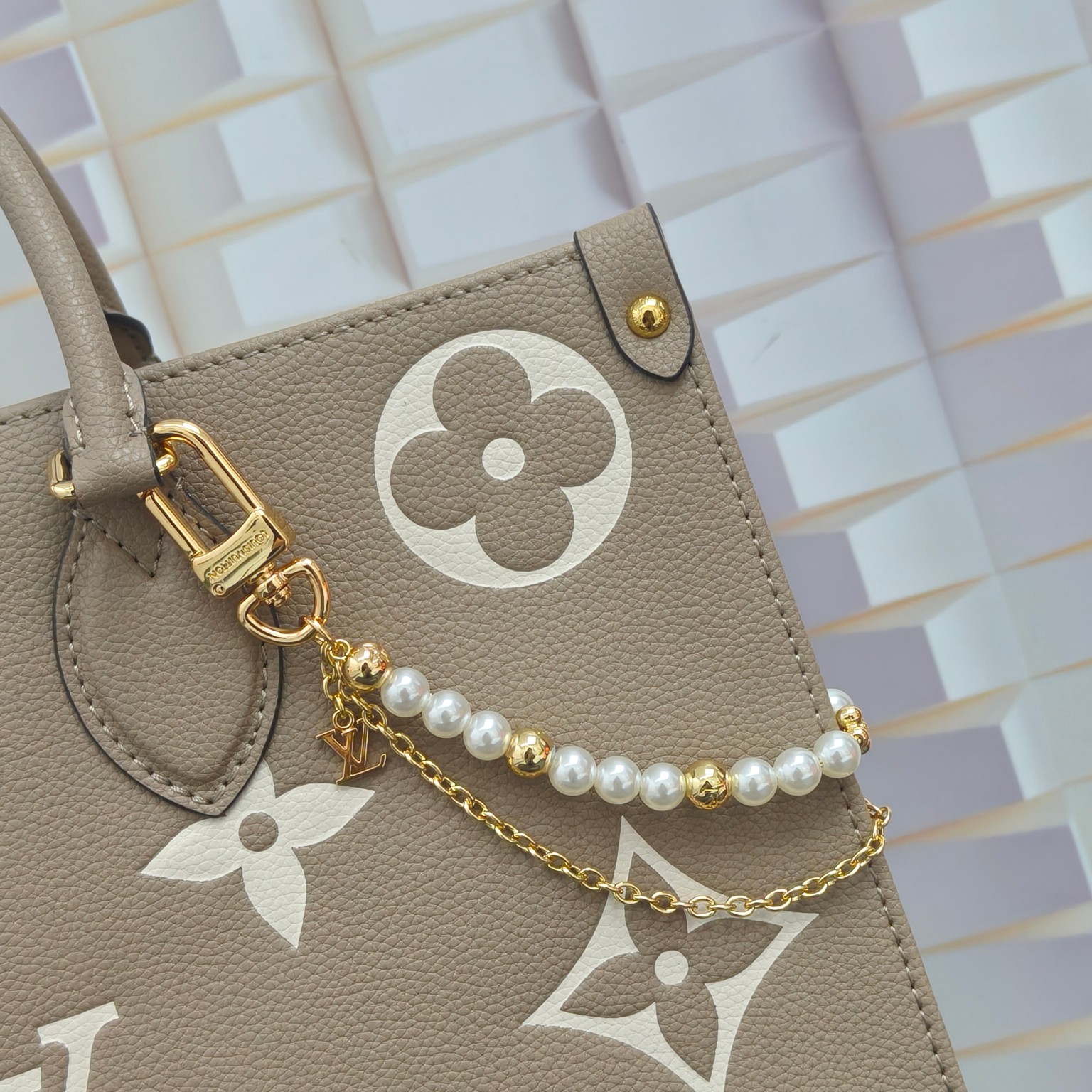 LV 腰带链以双链设计宣示潮流个性：一条融汇珠饰，并以金属串珠拼写 VUITTON 标识，另一条借链环释