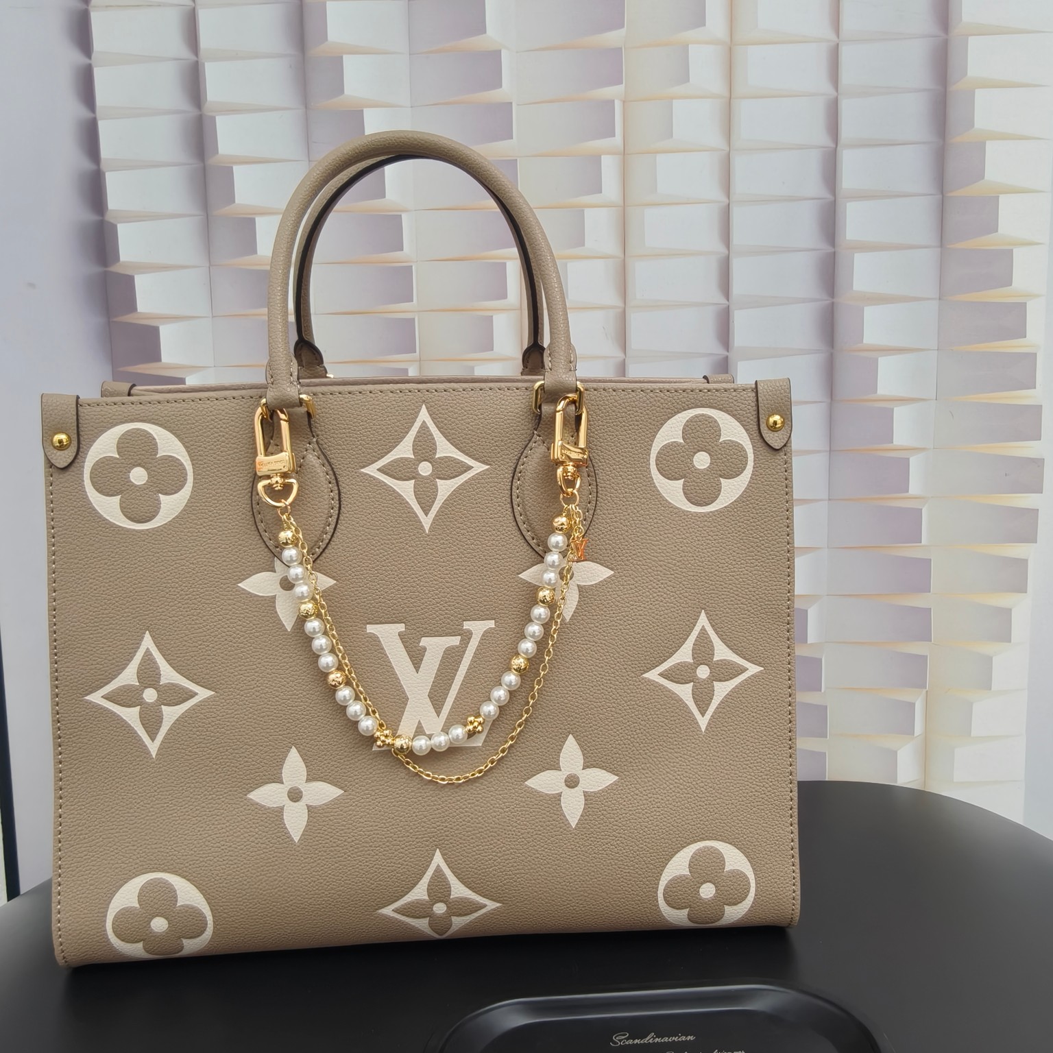 LV 腰带链以双链设计宣示潮流个性：一条融汇珠饰，并以金属串珠拼写 VUITTON 标识，另一条借链环释