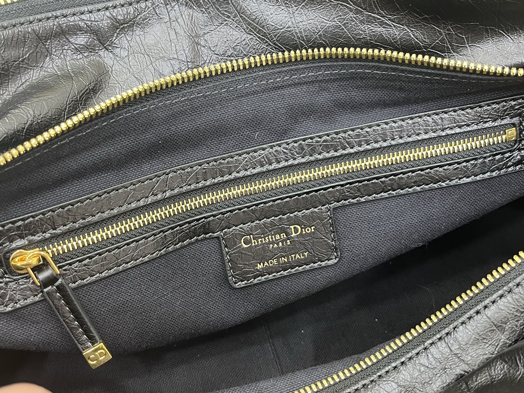 这款 Grand Tour 保龄球包是本季新品，于迪奥二零二五春夏成衣系列发布秀精彩亮相，实用摩登的设计饰以精致的细节。采用黑色褶皱牛皮革精心制作，质地柔软，正面饰以复古金色饰面金属 Christian Dior Paris 标志提升格调。多口袋设计，设有三个拉链隔层，中间隔层的两个大号皮革拉链头点缀以金属 Christian Dior Paris 标志。正面四个拉链口袋可整齐收纳各种小件日常用品。中号款式，搭配带搭扣的顶部皮革手柄和可调节、可拆卸的肩带，可手提或肩背。
尺寸：36 x 22.5 x 12 厘米（长 x 高 x 宽）
编号:M60

号牌:449091