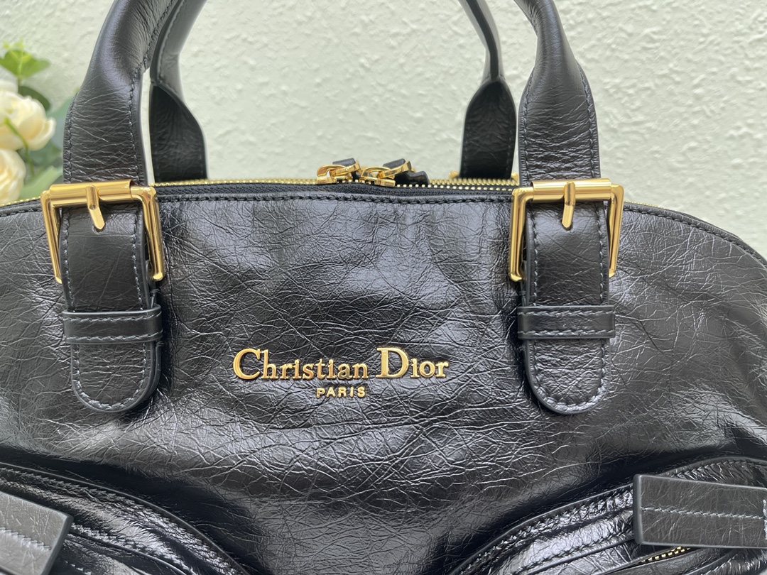 这款 Grand Tour 保龄球包是本季新品，于迪奥二零二五春夏成衣系列发布秀精彩亮相，实用摩登的设计饰以精致的细节。采用黑色褶皱牛皮革精心制作，质地柔软，正面饰以复古金色饰面金属 Christian Dior Paris 标志提升格调。多口袋设计，设有三个拉链隔层，中间隔层的两个大号皮革拉链头点缀以金属 Christian Dior Paris 标志。正面四个拉链口袋可整齐收纳各种小件日常用品。中号款式，搭配带搭扣的顶部皮革手柄和可调节、可拆卸的肩带，可手提或肩背。
尺寸：36 x 22.5 x 12 厘米（长 x 高 x 宽）
编号:M60

号牌:449091