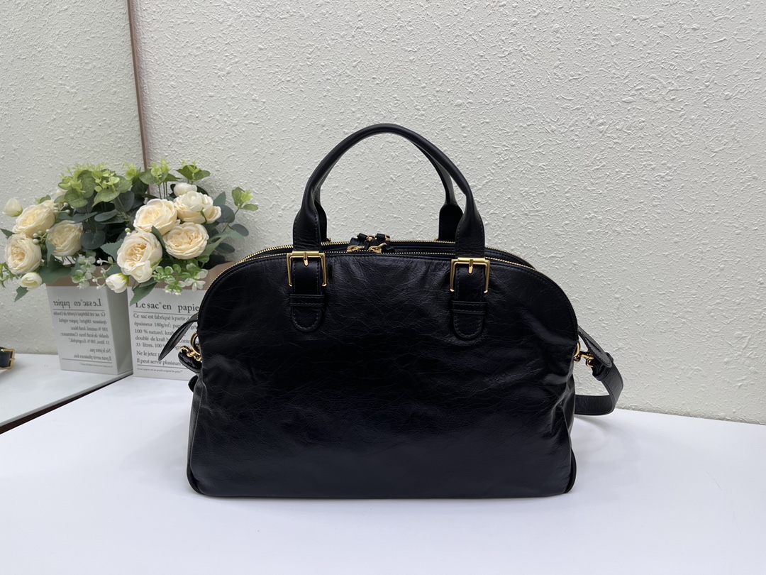 这款 Grand Tour 保龄球包是本季新品，于迪奥二零二五春夏成衣系列发布秀精彩亮相，实用摩登的设计饰以精致的细节。采用黑色褶皱牛皮革精心制作，质地柔软，正面饰以复古金色饰面金属 Christian Dior Paris 标志提升格调。多口袋设计，设有三个拉链隔层，中间隔层的两个大号皮革拉链头点缀以金属 Christian Dior Paris 标志。正面四个拉链口袋可整齐收纳各种小件日常用品。中号款式，搭配带搭扣的顶部皮革手柄和可调节、可拆卸的肩带，可手提或肩背。
尺寸：36 x 22.5 x 12 厘米（长 x 高 x 宽）
编号:M60

号牌:449091