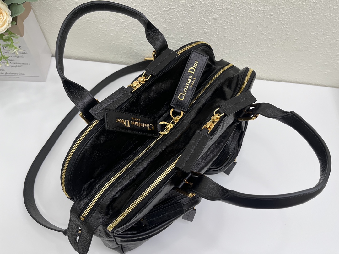 这款 Grand Tour 保龄球包是本季新品，于迪奥二零二五春夏成衣系列发布秀精彩亮相，实用摩登的设计饰以精致的细节。采用黑色褶皱牛皮革精心制作，质地柔软，正面饰以复古金色饰面金属 Christian Dior Paris 标志提升格调。多口袋设计，设有三个拉链隔层，中间隔层的两个大号皮革拉链头点缀以金属 Christian Dior Paris 标志。正面四个拉链口袋可整齐收纳各种小件日常用品。中号款式，搭配带搭扣的顶部皮革手柄和可调节、可拆卸的肩带，可手提或肩背。
尺寸：36 x 22.5 x 12 厘米（长 x 高 x 宽）
编号:M60

号牌:449091