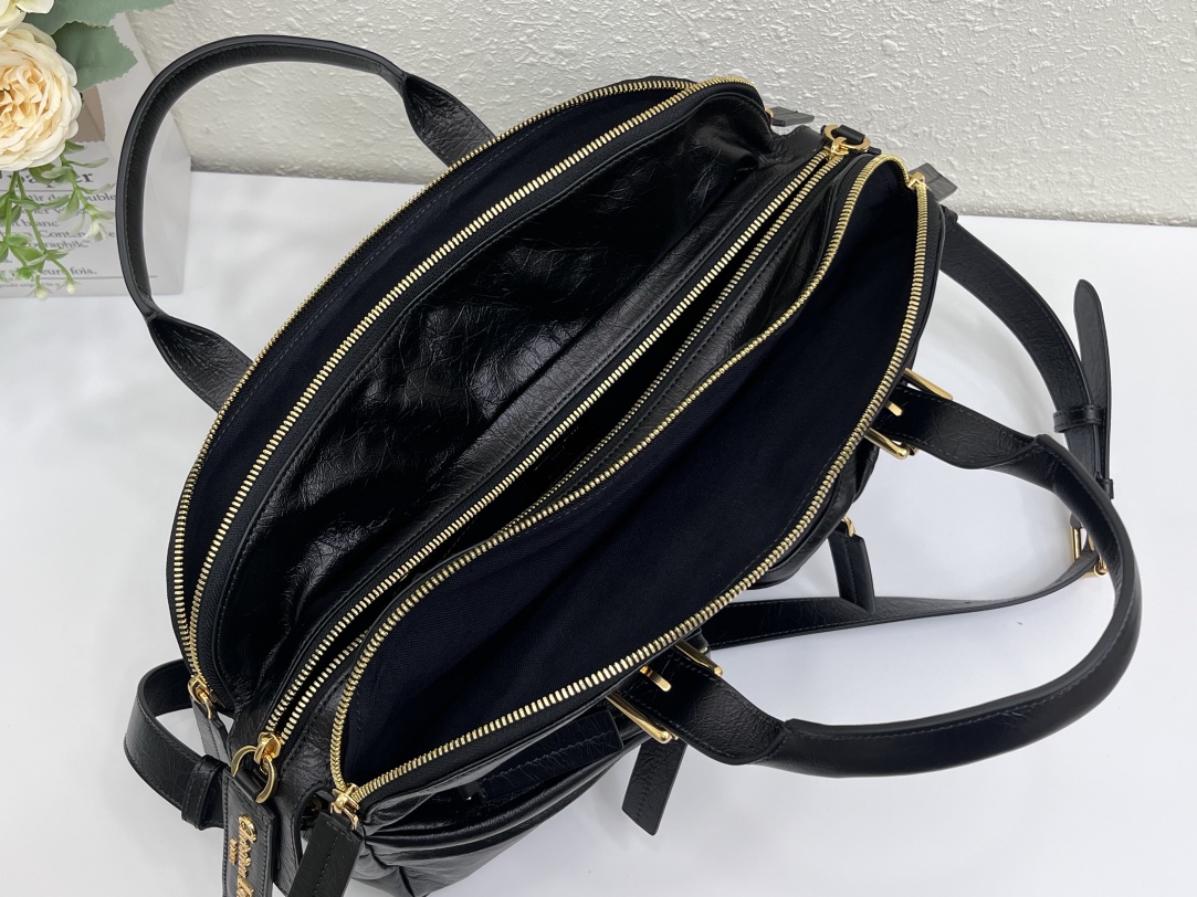 这款 Grand Tour 保龄球包是本季新品，于迪奥二零二五春夏成衣系列发布秀精彩亮相，实用摩登的设计饰以精致的细节。采用黑色褶皱牛皮革精心制作，质地柔软，正面饰以复古金色饰面金属 Christian Dior Paris 标志提升格调。多口袋设计，设有三个拉链隔层，中间隔层的两个大号皮革拉链头点缀以金属 Christian Dior Paris 标志。正面四个拉链口袋可整齐收纳各种小件日常用品。中号款式，搭配带搭扣的顶部皮革手柄和可调节、可拆卸的肩带，可手提或肩背。
尺寸：36 x 22.5 x 12 厘米（长 x 高 x 宽）
编号:M60

号牌:449091