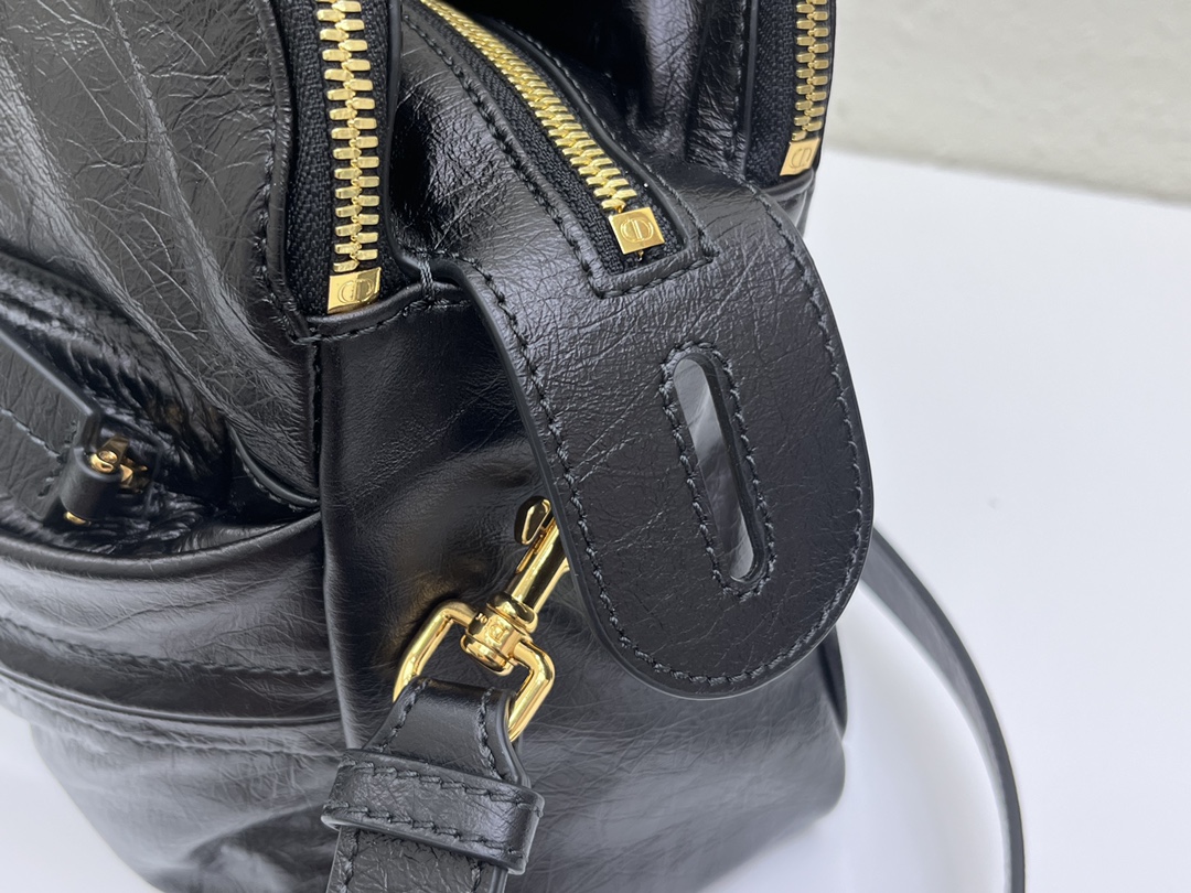 这款 Grand Tour 保龄球包是本季新品，于迪奥二零二五春夏成衣系列发布秀精彩亮相，实用摩登的设计饰以精致的细节。采用黑色褶皱牛皮革精心制作，质地柔软，正面饰以复古金色饰面金属 Christian Dior Paris 标志提升格调。多口袋设计，设有三个拉链隔层，中间隔层的两个大号皮革拉链头点缀以金属 Christian Dior Paris 标志。正面四个拉链口袋可整齐收纳各种小件日常用品。中号款式，搭配带搭扣的顶部皮革手柄和可调节、可拆卸的肩带，可手提或肩背。
尺寸：36 x 22.5 x 12 厘米（长 x 高 x 宽）
编号:M60

号牌:449091