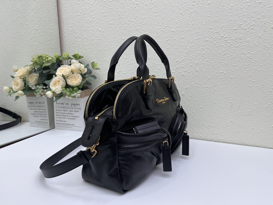 这款 Grand Tour 保龄球包是本季新品，于迪奥二零二五春夏成衣系列发布秀精彩亮相，实用摩登的设计饰以精致的细节。采用黑色褶皱牛皮革精心制作，质地柔软，正面饰以复古金色饰面金属 Christian Dior Paris 标志提升格调。多口袋设计，设有三个拉链隔层，中间隔层的两个大号皮革拉链头点缀以金属 Christian Dior Paris 标志。正面四个拉链口袋可整齐收纳各种小件日常用品。中号款式，搭配带搭扣的顶部皮革手柄和可调节、可拆卸的肩带，可手提或肩背。
尺寸：36 x 22.5 x 12 厘米（长 x 高 x 宽）
编号:M60

号牌:449091