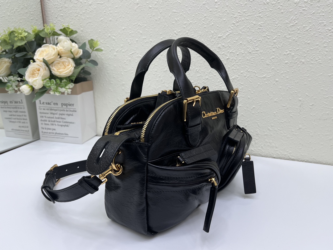 这款 Grand Tour 保龄球包是本季新品，于迪奥二零二五春夏成衣系列发布秀精彩亮相，实用摩登的设计饰以精致的细节。采用黑色褶皱牛皮革精心制作，质地柔软，正面饰以复古金色饰面金属 Christian Dior Paris 标志提升格调。多口袋设计，设有三个拉链隔层，中间隔层的两个大号皮革拉链头点缀以金属 Christian Dior Paris 标志。正面四个拉链口袋可整齐收纳各种小件日常用品。小号款式，搭配带搭扣的顶部皮革手柄和可调节、可拆卸的肩带，可手提或肩背。
尺寸：28 x 19 x 9.5 厘米（长 x 高 x 宽）
编号:M60

号牌:448591