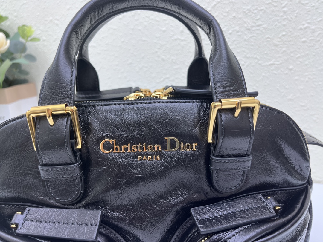 这款 Grand Tour 保龄球包是本季新品，于迪奥二零二五春夏成衣系列发布秀精彩亮相，实用摩登的设计饰以精致的细节。采用黑色褶皱牛皮革精心制作，质地柔软，正面饰以复古金色饰面金属 Christian Dior Paris 标志提升格调。多口袋设计，设有三个拉链隔层，中间隔层的两个大号皮革拉链头点缀以金属 Christian Dior Paris 标志。正面四个拉链口袋可整齐收纳各种小件日常用品。小号款式，搭配带搭扣的顶部皮革手柄和可调节、可拆卸的肩带，可手提或肩背。
尺寸：28 x 19 x 9.5 厘米（长 x 高 x 宽）
编号:M60

号牌:448591