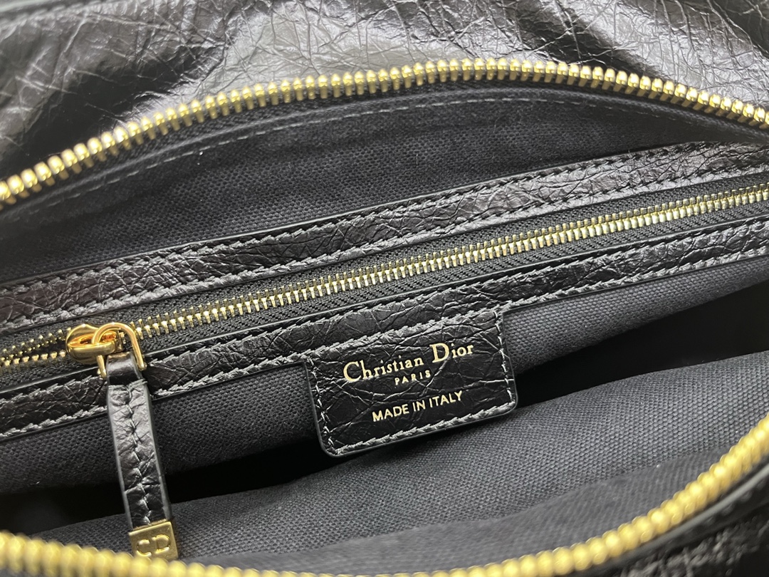 这款 Grand Tour 保龄球包是本季新品，于迪奥二零二五春夏成衣系列发布秀精彩亮相，实用摩登的设计饰以精致的细节。采用黑色褶皱牛皮革精心制作，质地柔软，正面饰以复古金色饰面金属 Christian Dior Paris 标志提升格调。多口袋设计，设有三个拉链隔层，中间隔层的两个大号皮革拉链头点缀以金属 Christian Dior Paris 标志。正面四个拉链口袋可整齐收纳各种小件日常用品。小号款式，搭配带搭扣的顶部皮革手柄和可调节、可拆卸的肩带，可手提或肩背。
尺寸：28 x 19 x 9.5 厘米（长 x 高 x 宽）
编号:M60

号牌:448591