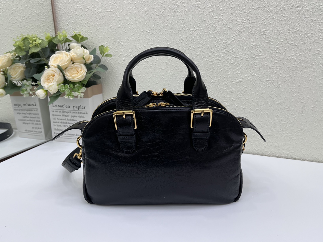 这款 Grand Tour 保龄球包是本季新品，于迪奥二零二五春夏成衣系列发布秀精彩亮相，实用摩登的设计饰以精致的细节。采用黑色褶皱牛皮革精心制作，质地柔软，正面饰以复古金色饰面金属 Christian Dior Paris 标志提升格调。多口袋设计，设有三个拉链隔层，中间隔层的两个大号皮革拉链头点缀以金属 Christian Dior Paris 标志。正面四个拉链口袋可整齐收纳各种小件日常用品。小号款式，搭配带搭扣的顶部皮革手柄和可调节、可拆卸的肩带，可手提或肩背。
尺寸：28 x 19 x 9.5 厘米（长 x 高 x 宽）
编号:M60

号牌:448591