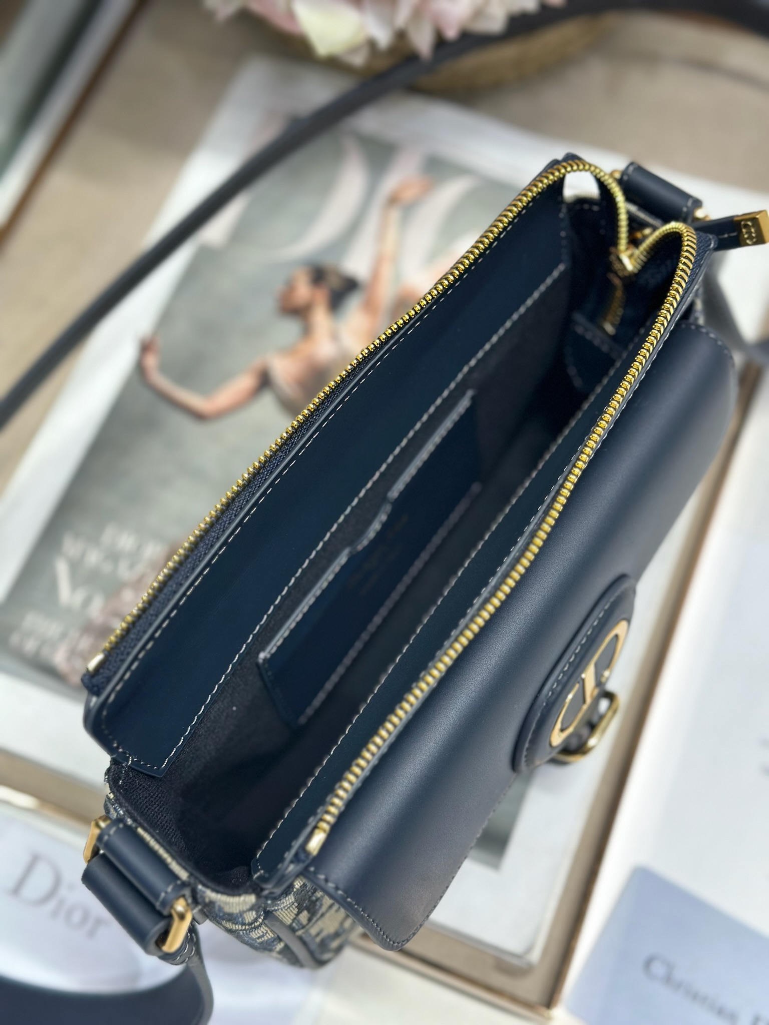 Dior 新款波比拉链小包 「蓝D布配皮」
这款波比拉链手袋是二零二五春夏成衣系列新品，采用蓝色 Oblique 印花面料等材质精心制作，优雅实用的设计提升该系列的格调。同色调光滑牛皮革翻盖饰以复古金色饰面金属细节，饰以拉链开口，配可调节肩带，手提、肩背或斜挎。p560

翻盖开合
拉链开口
可调节、可拆卸的皮革带
内部插袋

型号：2358
尺寸：20 X13.5 X5.5 厘米（长 x 高 x 宽）