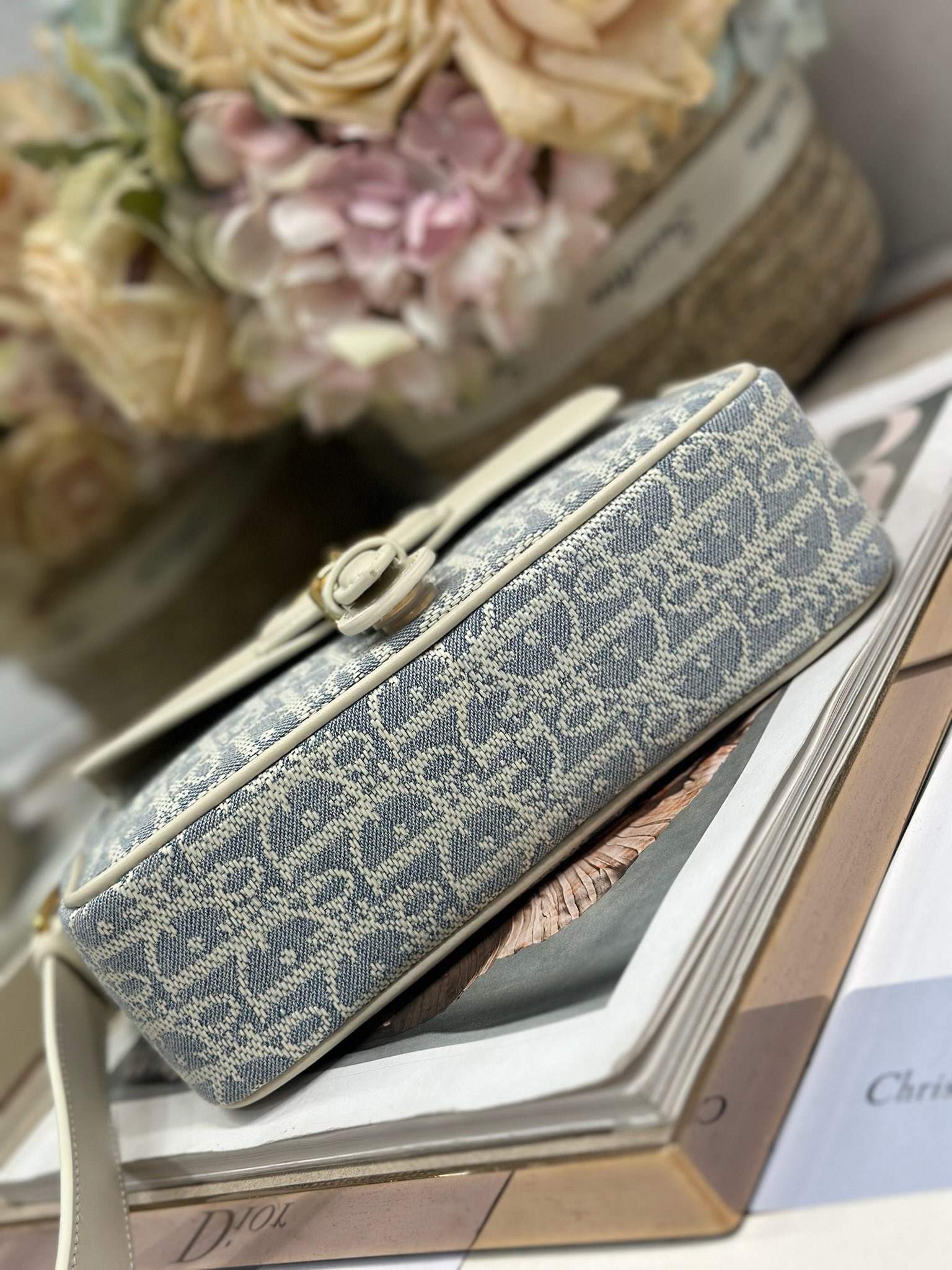 Dior 新款波比拉链小包 「椰子蓝D布配皮」
这款波比拉链手袋是二零二五春夏成衣系列新品，采用椰子蓝 Oblique 印花面料等材质精心制作，优雅实用的设计提升该系列的格调。浅饼干色调光滑牛皮革翻盖饰以复古金色饰面金属细节，饰以拉链开口，配可调节肩带，手提、肩背或斜挎。p560

翻盖开合
拉链开口
可调节、可拆卸的皮革带
内部插袋

型号：2358
尺寸：20 X13.5 X5.5 厘米（长 x 高 x 宽）