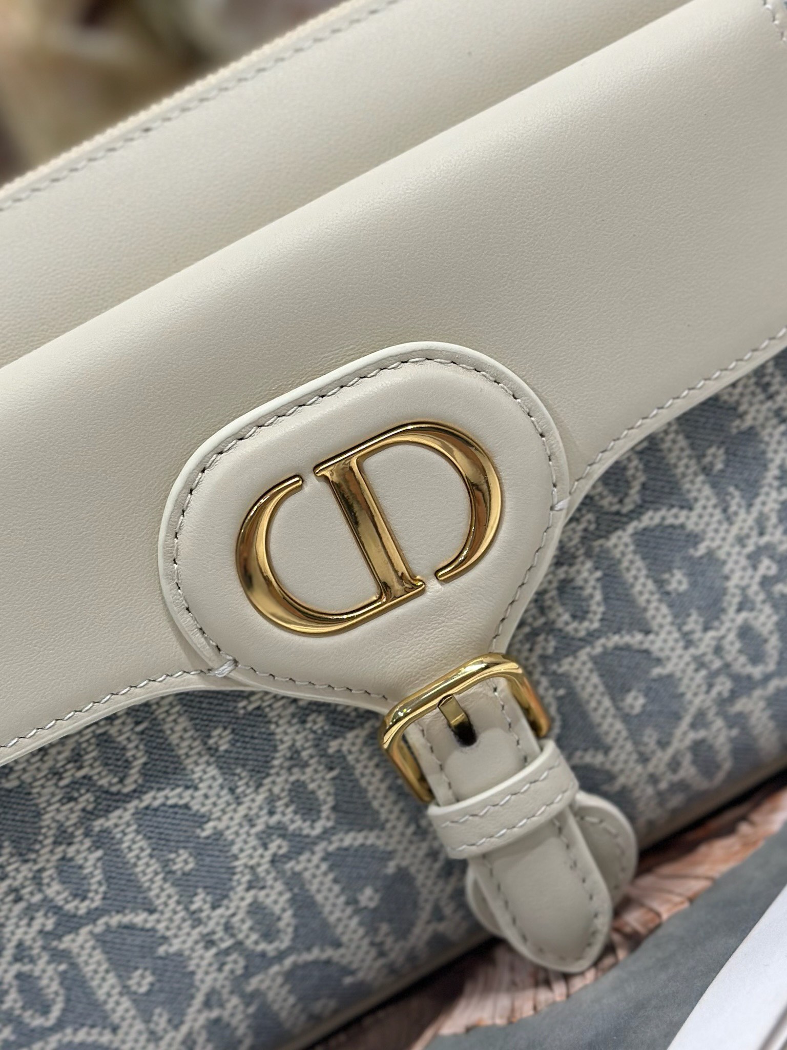 Dior 新款波比拉链小包 「椰子蓝D布配皮」
这款波比拉链手袋是二零二五春夏成衣系列新品，采用椰子蓝 Oblique 印花面料等材质精心制作，优雅实用的设计提升该系列的格调。浅饼干色调光滑牛皮革翻盖饰以复古金色饰面金属细节，饰以拉链开口，配可调节肩带，手提、肩背或斜挎。p560

翻盖开合
拉链开口
可调节、可拆卸的皮革带
内部插袋

型号：2358
尺寸：20 X13.5 X5.5 厘米（长 x 高 x 宽）
