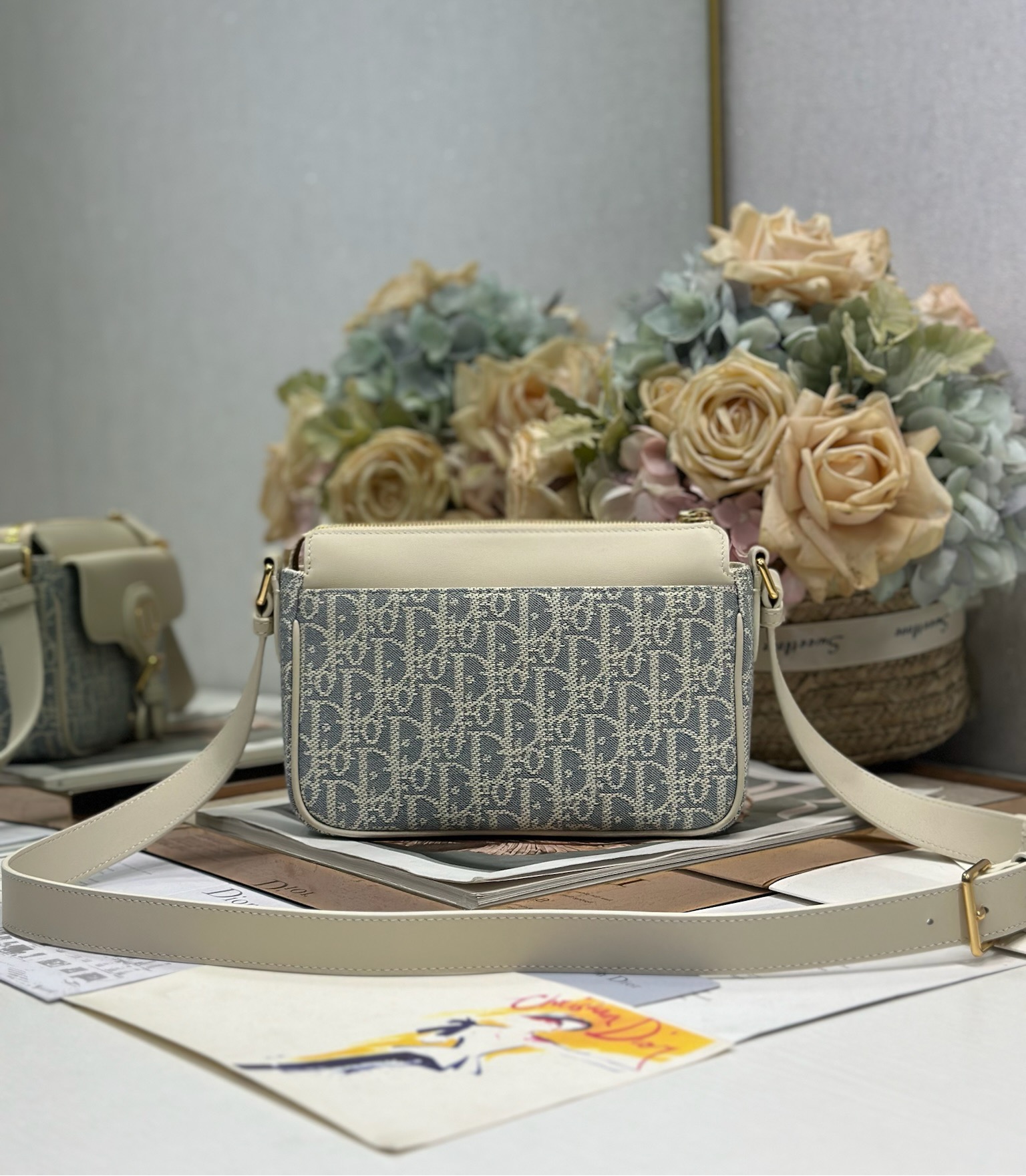 Dior 新款波比拉链小包 「椰子蓝D布配皮」
这款波比拉链手袋是二零二五春夏成衣系列新品，采用椰子蓝 Oblique 印花面料等材质精心制作，优雅实用的设计提升该系列的格调。浅饼干色调光滑牛皮革翻盖饰以复古金色饰面金属细节，饰以拉链开口，配可调节肩带，手提、肩背或斜挎。p560

翻盖开合
拉链开口
可调节、可拆卸的皮革带
内部插袋

型号：2358
尺寸：20 X13.5 X5.5 厘米（长 x 高 x 宽）