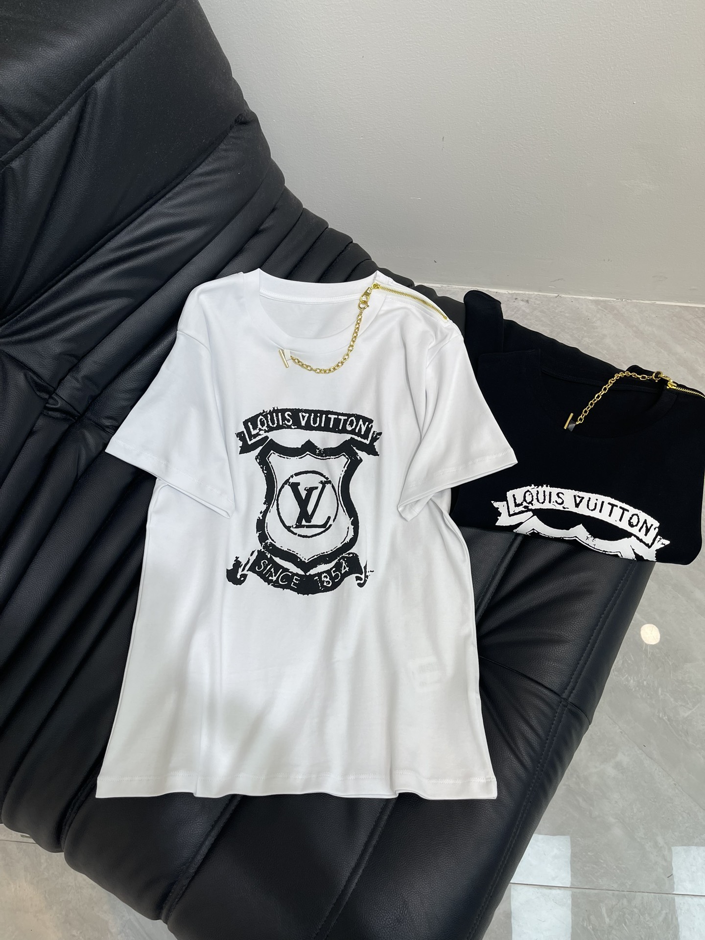 NO:457530,Louis Vuitto*25 early autumn new printed chain short-sleeved T-shirt custom YB twill cotton material breathable and comfortable, full texture. Regular short-sleeved T-shirt cut highlights the brand style. Made of gram-weight pure cotton, slightly elastic, and slimming visual effect. The chest is decorated with retro aging letter logo and shield badge. Single-side shoulder zipper is connected to the neckline to create a necklace-like gorgeous effect. Highlights highlight high-end style. The inner wear is brilliant and fashionable. SML,,louis vuitton, T-shirt,tees, t-shirt,necklace,alexander wang19860909Louis Vuitto*25早秋新款印花链条短袖T恤 定制YB斜纹全棉材质 透气舒适 质感十足 常规短袖T恤裁剪 凸显品牌格调 采用克重纯棉制成 略带有弹力 呈现显瘦视觉效果 胸前用复古做旧感字母标识和盾牌徽章装饰 单侧肩膀拉链与领口连接 打造项链般的华丽效果 亮点突出 彰显高级格调 单穿内搭都出彩时髦 SML,,louis vuitton,T-shirt,tees，t-shirt,necklace,alexander wang,Women's clothing