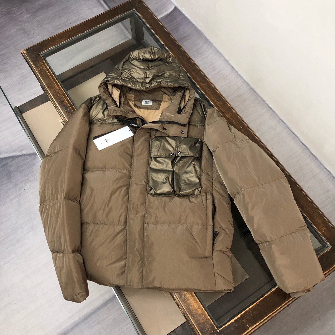 p625.00 CP.COMPANY新款专柜同步，CP经典防风镜片羽绒服，90进口羽绒 特殊高密记忆面料原厂染色防水配色，防风保暖袖口具备上身体感保温舒适度极好  简洁大方的设计 深受户外旅游爱好人士偏爱 也适合平时商务穿着的百搭款 所有辅料原版定制 实物拍照 现货供应！！  
颜色：黑色  卡其色  灰色
尺码：M-L-XL-2XL
​