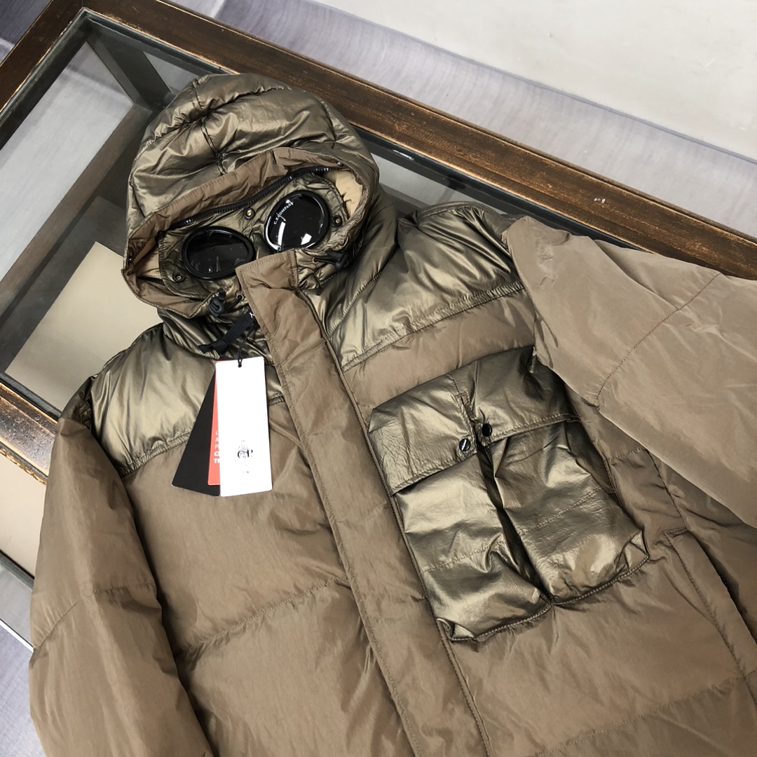 p625.00 CP.COMPANY新款专柜同步，CP经典防风镜片羽绒服，90进口羽绒 特殊高密记忆面料原厂染色防水配色，防风保暖袖口具备上身体感保温舒适度极好  简洁大方的设计 深受户外旅游爱好人士偏爱 也适合平时商务穿着的百搭款 所有辅料原版定制 实物拍照 现货供应！！  
颜色：黑色  卡其色  灰色
尺码：M-L-XL-2XL
​