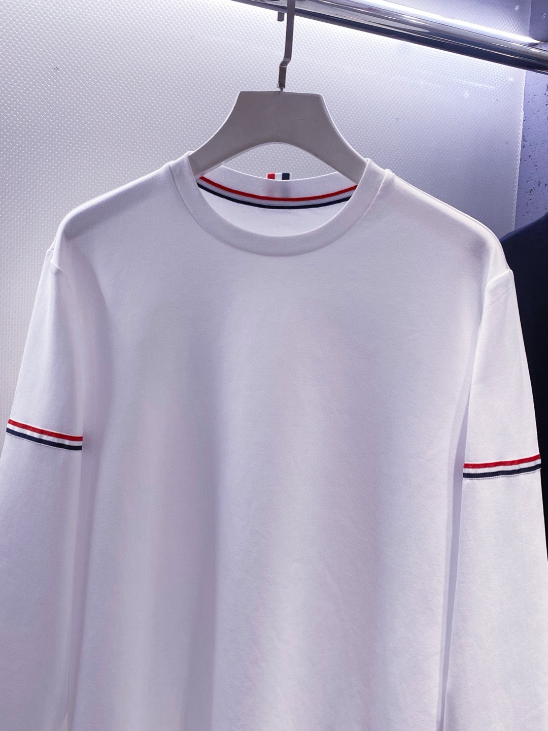 TB~袖臂经典织带嵌花薄太空棉长袖T恤衫
秋冬新款
ThomB&hellip;太空薄棉长袖T恤、解锁先锋穿搭密码.. 将经典与创新融合，用细节诠释品质，邀你共赴这场时尚之约，解锁独属于你的潮流穿搭。
袖臂处经典织带标识嵌花，红白蓝三色交织，是Thom Br..标志性元素，以精湛工艺融入衣物，如同品牌名片，举手投足间彰显独特品味，是低调中的高调宣言 ，无论是日常出街还是社交场合，都能让你成为目光焦点。
匠心剪裁，设计感拉满。前短后长的衣摆设计，打破常规，塑造出独特的层次感，行走间衣角轻扬，尽显灵动与随性；下摆两侧开叉处同样点缀织带，为整体造型增添细节亮点，更在不经意间流露精致态度，轻松提升穿搭的时髦指数 。
选用太空薄棉面料，奢护每寸肌肤，轻盈似云朵，贴肤感满分，透气性绝佳，能保持清爽。细密的纺织工艺，让面料柔软又有韧性，耐穿且不易变形，为你带来持久的舒适体验。是休闲潮流时尚的首选之一。

颜色：白色、黑色
规格：S--XXL
    P210
M码:肩宽45.胸围106. 前衣长66. 后衣长71.袖长62
L码：肩宽46.胸围110.前衣长67.后衣长72.袖长63