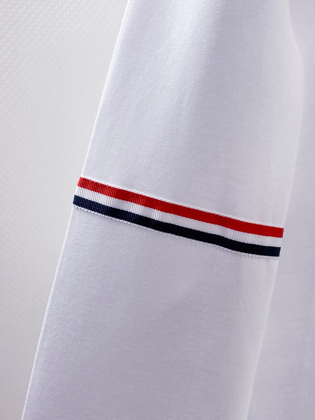 TB~袖臂经典织带嵌花薄太空棉长袖T恤衫
秋冬新款
ThomB&hellip;太空薄棉长袖T恤、解锁先锋穿搭密码.. 将经典与创新融合，用细节诠释品质，邀你共赴这场时尚之约，解锁独属于你的潮流穿搭。
袖臂处经典织带标识嵌花，红白蓝三色交织，是Thom Br..标志性元素，以精湛工艺融入衣物，如同品牌名片，举手投足间彰显独特品味，是低调中的高调宣言 ，无论是日常出街还是社交场合，都能让你成为目光焦点。
匠心剪裁，设计感拉满。前短后长的衣摆设计，打破常规，塑造出独特的层次感，行走间衣角轻扬，尽显灵动与随性；下摆两侧开叉处同样点缀织带，为整体造型增添细节亮点，更在不经意间流露精致态度，轻松提升穿搭的时髦指数 。
选用太空薄棉面料，奢护每寸肌肤，轻盈似云朵，贴肤感满分，透气性绝佳，能保持清爽。细密的纺织工艺，让面料柔软又有韧性，耐穿且不易变形，为你带来持久的舒适体验。是休闲潮流时尚的首选之一。

颜色：白色、黑色
规格：S--XXL
    P210
M码:肩宽45.胸围106. 前衣长66. 后衣长71.袖长62
L码：肩宽46.胸围110.前衣长67.后衣长72.袖长63