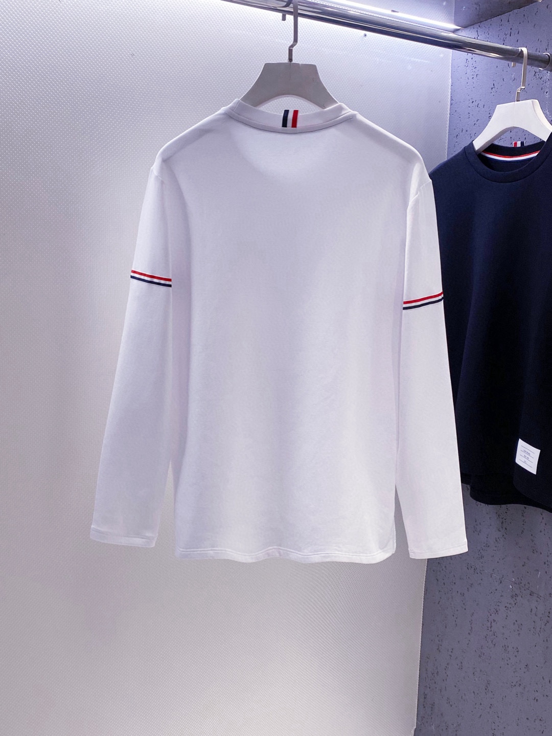 TB~袖臂经典织带嵌花薄太空棉长袖T恤衫
秋冬新款
ThomB&hellip;太空薄棉长袖T恤、解锁先锋穿搭密码.. 将经典与创新融合，用细节诠释品质，邀你共赴这场时尚之约，解锁独属于你的潮流穿搭。
袖臂处经典织带标识嵌花，红白蓝三色交织，是Thom Br..标志性元素，以精湛工艺融入衣物，如同品牌名片，举手投足间彰显独特品味，是低调中的高调宣言 ，无论是日常出街还是社交场合，都能让你成为目光焦点。
匠心剪裁，设计感拉满。前短后长的衣摆设计，打破常规，塑造出独特的层次感，行走间衣角轻扬，尽显灵动与随性；下摆两侧开叉处同样点缀织带，为整体造型增添细节亮点，更在不经意间流露精致态度，轻松提升穿搭的时髦指数 。
选用太空薄棉面料，奢护每寸肌肤，轻盈似云朵，贴肤感满分，透气性绝佳，能保持清爽。细密的纺织工艺，让面料柔软又有韧性，耐穿且不易变形，为你带来持久的舒适体验。是休闲潮流时尚的首选之一。

颜色：白色、黑色
规格：S--XXL
    P210
M码:肩宽45.胸围106. 前衣长66. 后衣长71.袖长62
L码：肩宽46.胸围110.前衣长67.后衣长72.袖长63