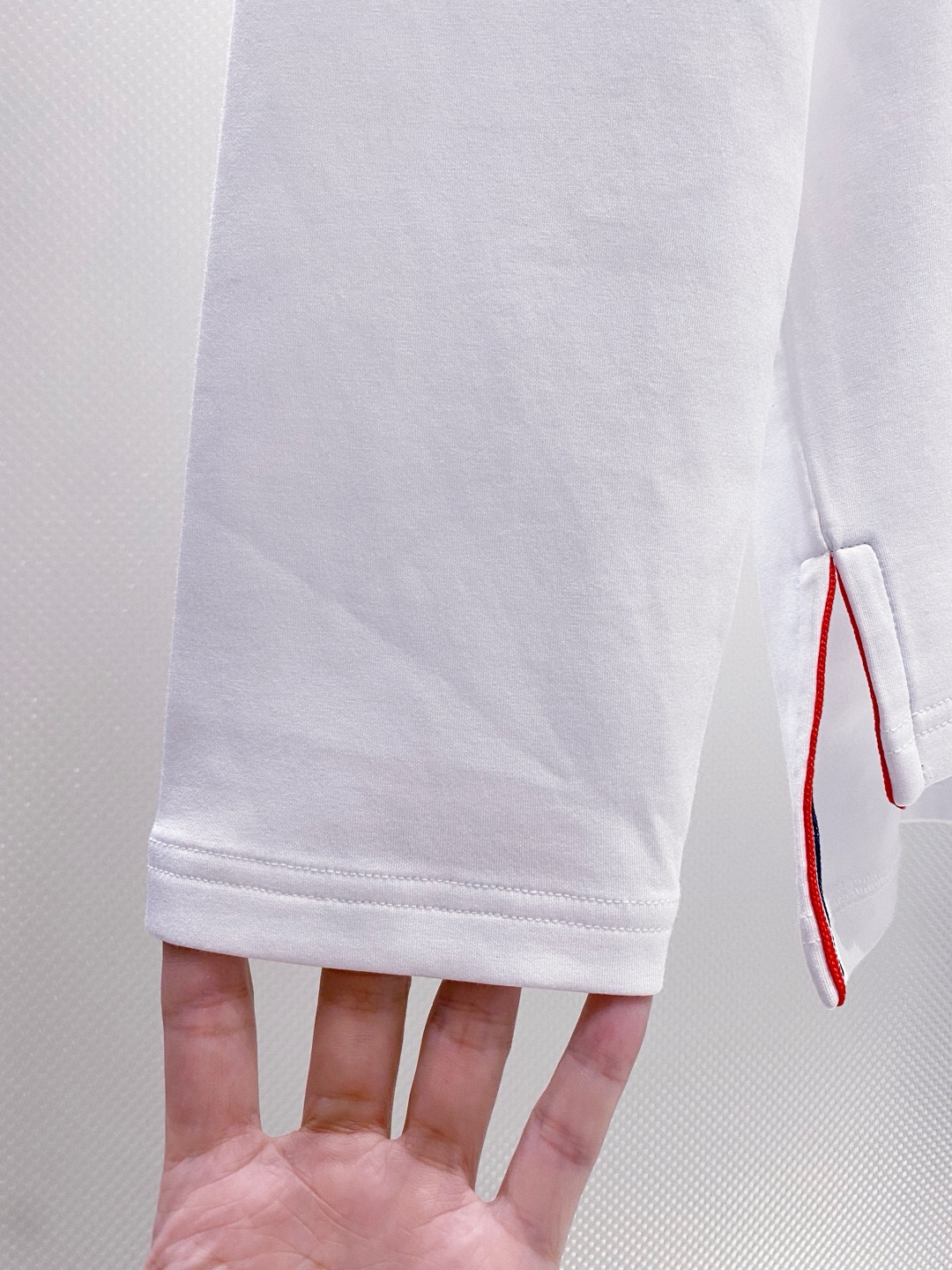 TB~袖臂经典织带嵌花薄太空棉长袖T恤衫
秋冬新款
ThomB&hellip;太空薄棉长袖T恤、解锁先锋穿搭密码.. 将经典与创新融合，用细节诠释品质，邀你共赴这场时尚之约，解锁独属于你的潮流穿搭。
袖臂处经典织带标识嵌花，红白蓝三色交织，是Thom Br..标志性元素，以精湛工艺融入衣物，如同品牌名片，举手投足间彰显独特品味，是低调中的高调宣言 ，无论是日常出街还是社交场合，都能让你成为目光焦点。
匠心剪裁，设计感拉满。前短后长的衣摆设计，打破常规，塑造出独特的层次感，行走间衣角轻扬，尽显灵动与随性；下摆两侧开叉处同样点缀织带，为整体造型增添细节亮点，更在不经意间流露精致态度，轻松提升穿搭的时髦指数 。
选用太空薄棉面料，奢护每寸肌肤，轻盈似云朵，贴肤感满分，透气性绝佳，能保持清爽。细密的纺织工艺，让面料柔软又有韧性，耐穿且不易变形，为你带来持久的舒适体验。是休闲潮流时尚的首选之一。

颜色：白色、黑色
规格：S--XXL
    P210
M码:肩宽45.胸围106. 前衣长66. 后衣长71.袖长62
L码：肩宽46.胸围110.前衣长67.后衣长72.袖长63