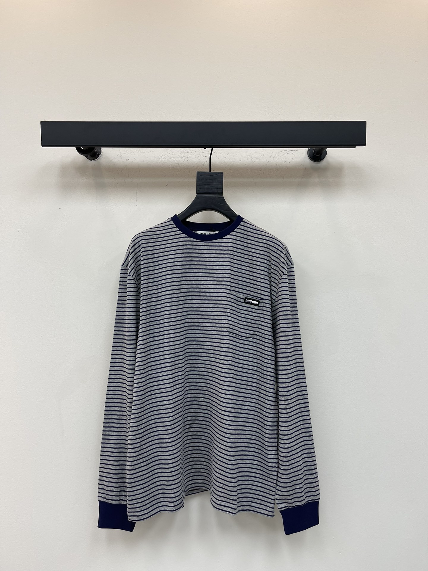 NO:535566,MiuMi* 25 early autumn new basic style narrow striped logo long sleeve T-shirt丨Exclusive yb development!  High-end production!  With the gray-bottomed blue pinstripes as the core, the retro academy style is blowing; the neckline and cuffs are embellished with hidden blue ribs, which are neat and layered. The black-bottomed white-lined small logo on the left chest is low-key to show the brand identity. The pure cotton fabric is soft and skin-friendly, and the loose shoulder-loose style is extremely inclusive to the figure, truly achieving the same versatility of men and women. The precise stripe alignment process takes time and materials, and restores the exquisite texture of the brand from the details. It can be adapted to both single-wearing and layering or commuting leisure. It can be called the 'evergreen basic style' in the wardrobe of the four seasons. SML, miumiu, alexander wang19860909MiuMi* 25早秋新款基础款窄条纹logo长袖 T 恤丨独家yb开发！高版出品！以灰底藏蓝细条纹为核心,复古学院风扑面而来；领口与袖口点缀藏蓝罗纹,利落又具层次感.左胸处黑底白字小标低调彰显品牌身份, 纯棉面料柔软亲肤,宽松落肩版型对身材包容性极强,真正实现男女同款百搭.条纹精准对位工艺耗时费料,从细节处还原品牌精致质感,无论是单穿叠搭还是通勤休闲都能适配,堪称四季衣橱里的“常青基础款”.SML,,miumiu,alexander wang,Women's clothing