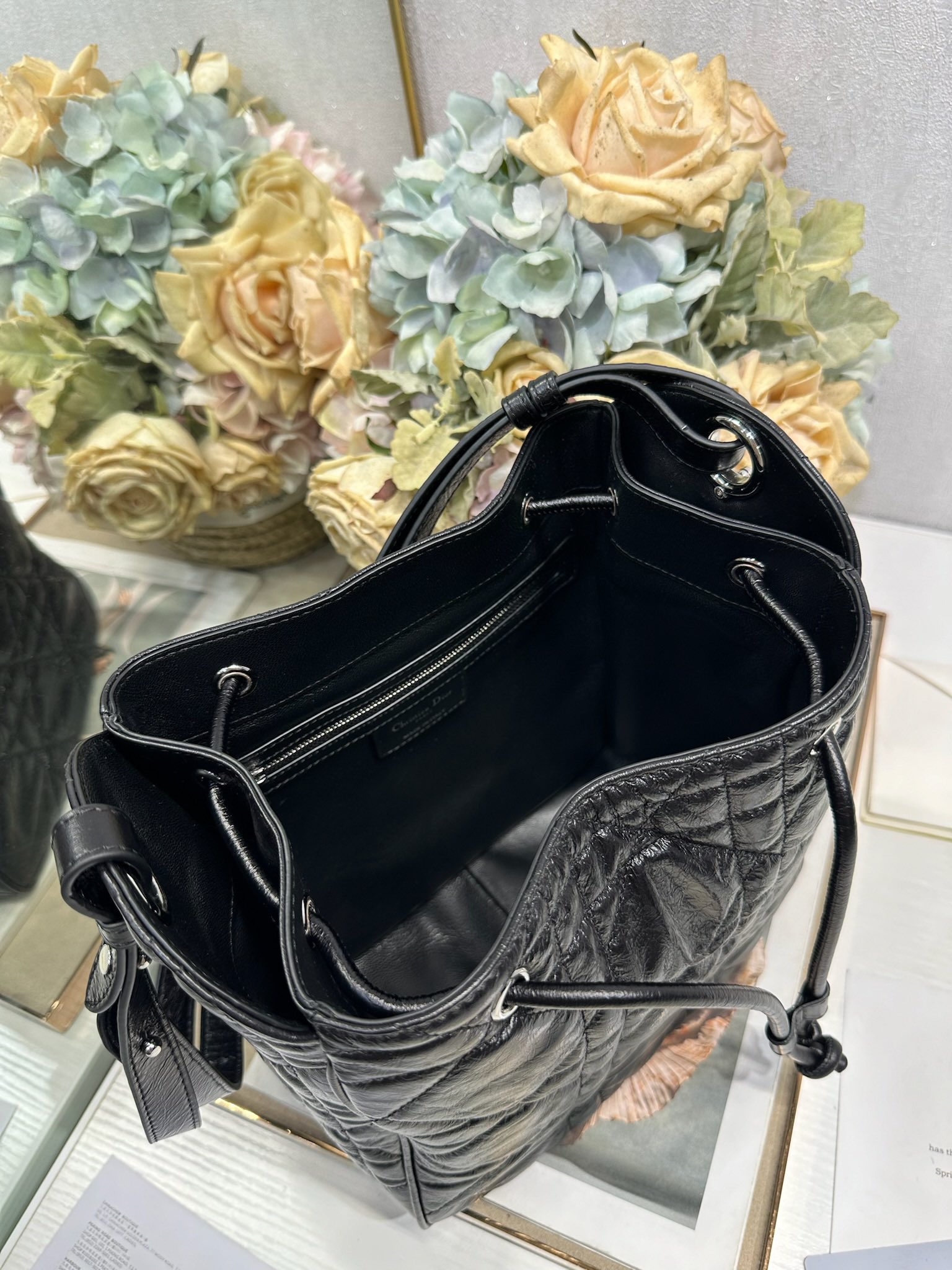 ✅中号 D-Motion 手袋「黑色褶皱」带可扫描高版本163变码芯片！
这款 D-Motion 手袋是二零二五冬季成衣系列新品，时尚实用的桶式设计，别具一格。采用黑色褶皱等材质精心制作，饰以藤格纹缉面线，柔软的版型搭配抽绳开合。带有宽敞的内部隔层、拉链口袋及两个侧面插袋，可收纳各种日常用品。中号款式，饰以银扣饰面金属 D.I.O.R. 吊饰更显精致，搭配滑动设计的可调节肩带，可肩背或斜挎。p700

D.I.O.R. 吊饰
抽绳开合
可调节皮革肩带
2 个内部插袋
内部拉链口袋

型号：2852
尺寸：23 x 24 x 13 厘米（长 x 高 x 宽）
可收纳 1 个 Voyageur 钱包、1 部手机、1 个卡夹、太阳眼镜和唇膏