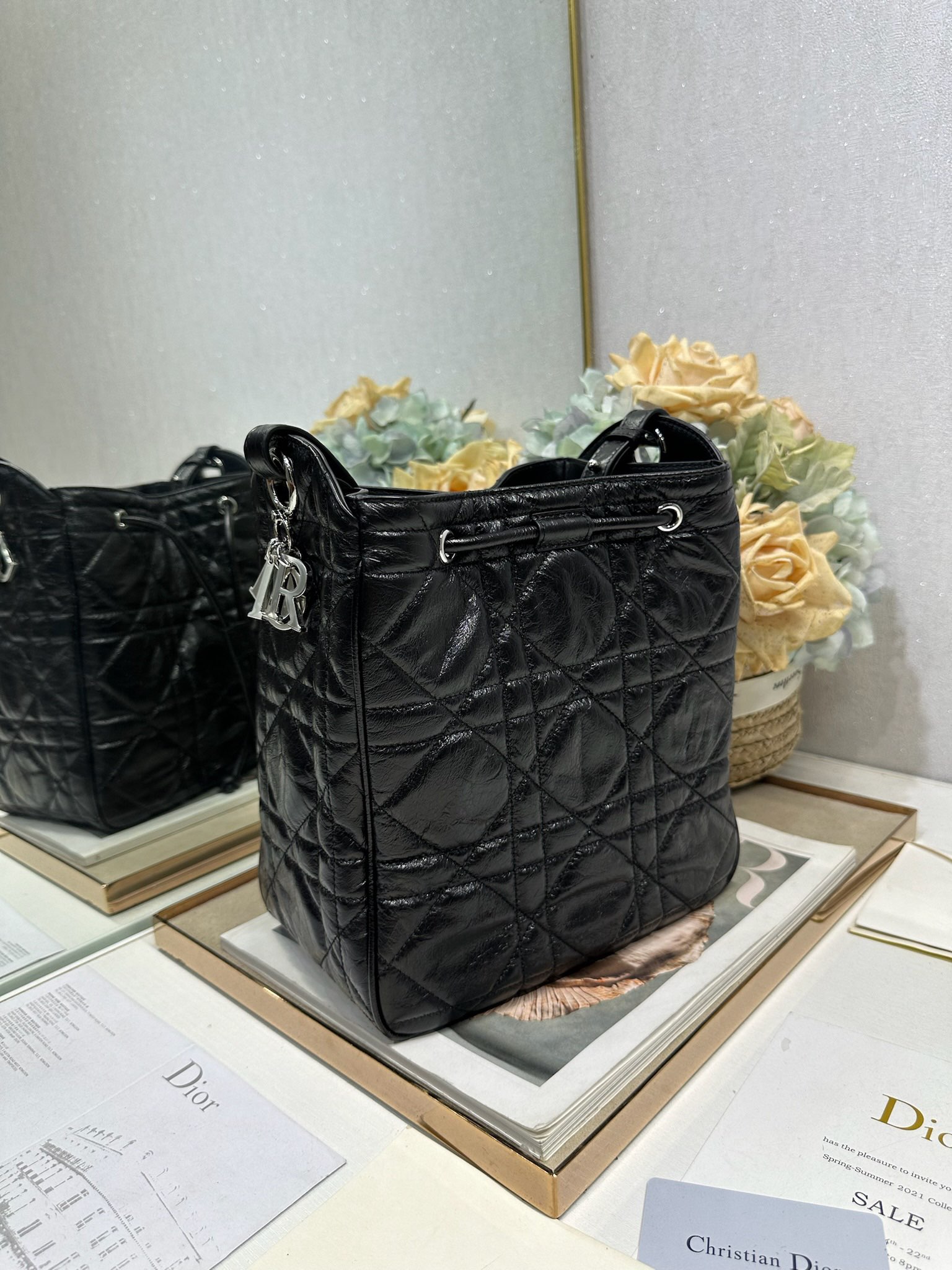 ✅中号 D-Motion 手袋「黑色褶皱」带可扫描高版本163变码芯片！
这款 D-Motion 手袋是二零二五冬季成衣系列新品，时尚实用的桶式设计，别具一格。采用黑色褶皱等材质精心制作，饰以藤格纹缉面线，柔软的版型搭配抽绳开合。带有宽敞的内部隔层、拉链口袋及两个侧面插袋，可收纳各种日常用品。中号款式，饰以银扣饰面金属 D.I.O.R. 吊饰更显精致，搭配滑动设计的可调节肩带，可肩背或斜挎。p700

D.I.O.R. 吊饰
抽绳开合
可调节皮革肩带
2 个内部插袋
内部拉链口袋

型号：2852
尺寸：23 x 24 x 13 厘米（长 x 高 x 宽）
可收纳 1 个 Voyageur 钱包、1 部手机、1 个卡夹、太阳眼镜和唇膏