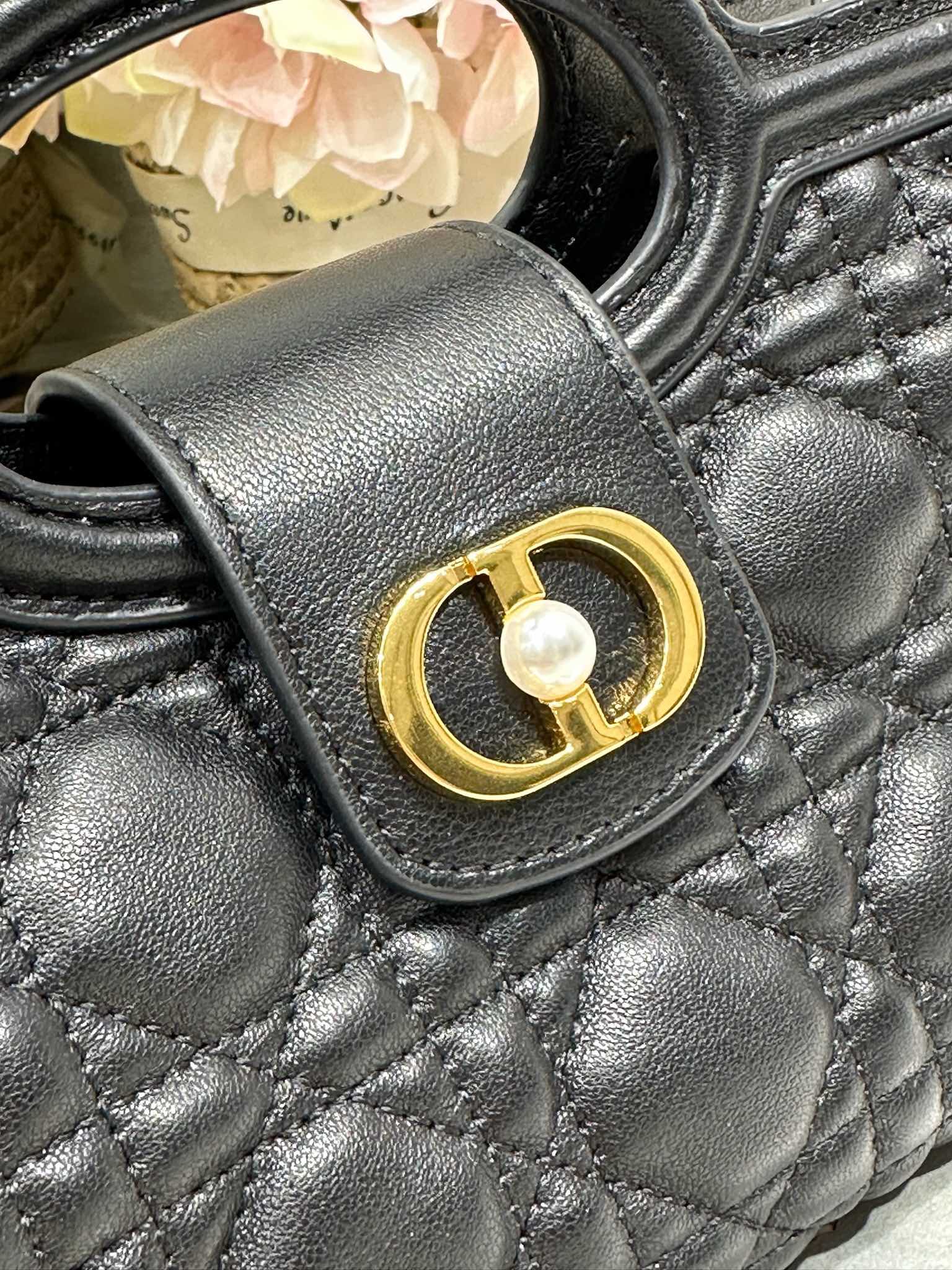 Dior Jolie Top Handle 迷你链条手袋「黑色」
这款 Dior Jolie Top Handle 迷你链条手袋是二零二六早春成衣系列新品，呈现出优雅精致的设计。采用黑色羊皮革精心制作，饰以藤格纹，翻盖点缀以金色饰面金属 CD 标志和白色树脂珠饰。内设一个隔层，可收纳各种日常用品。搭配双顶部手柄和可调节、可拆卸 CD 链条肩带，肩带由皮革带和 CD 链环组成，饰以白色树脂珠饰，可舒适手提、肩背或斜挎，可与日常或晚装造型搭配。
磁性翻盖开合正面饰以 CD 扣环和白色树脂珠饰
1 个隔层
双顶部皮革手柄
可调节、可拆卸的链条饰以树脂珠饰和皮革带

型号：3123
尺寸：18.5 x 13 x 8.5 厘米（长 x 高 x 宽）
可收纳 1 部手机、1 个卡夹、太阳眼镜和唇膏