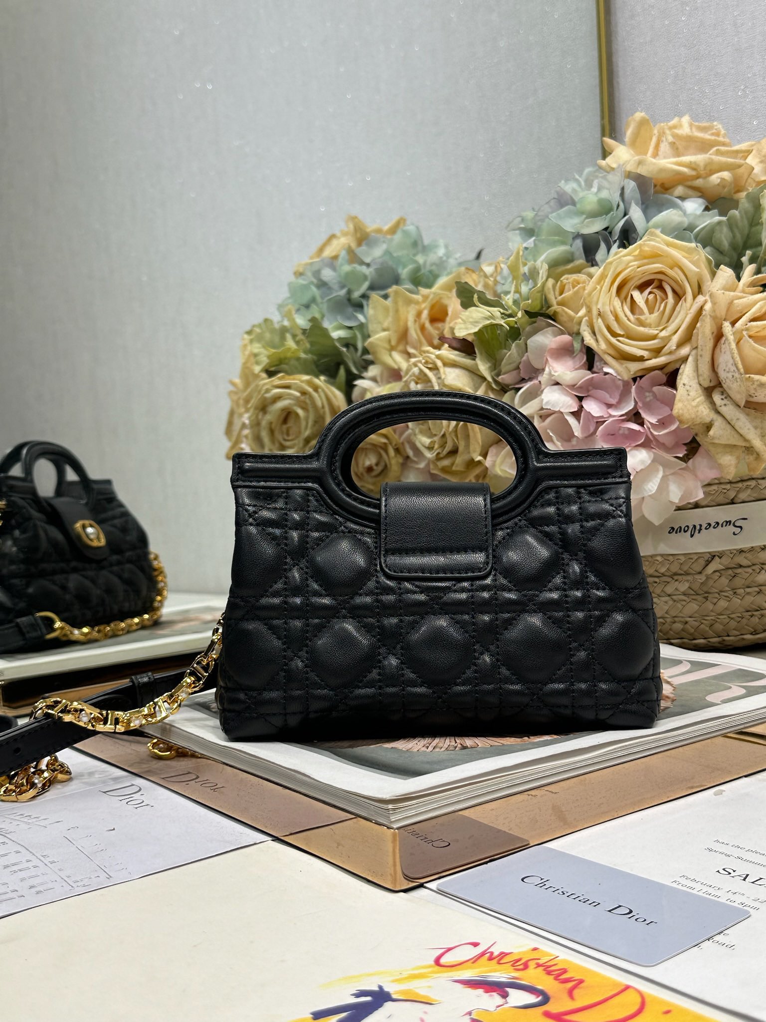 Dior Jolie Top Handle 迷你链条手袋「黑色」
这款 Dior Jolie Top Handle 迷你链条手袋是二零二六早春成衣系列新品，呈现出优雅精致的设计。采用黑色羊皮革精心制作，饰以藤格纹，翻盖点缀以金色饰面金属 CD 标志和白色树脂珠饰。内设一个隔层，可收纳各种日常用品。搭配双顶部手柄和可调节、可拆卸 CD 链条肩带，肩带由皮革带和 CD 链环组成，饰以白色树脂珠饰，可舒适手提、肩背或斜挎，可与日常或晚装造型搭配。
磁性翻盖开合正面饰以 CD 扣环和白色树脂珠饰
1 个隔层
双顶部皮革手柄
可调节、可拆卸的链条饰以树脂珠饰和皮革带

型号：3123
尺寸：18.5 x 13 x 8.5 厘米（长 x 高 x 宽）
可收纳 1 部手机、1 个卡夹、太阳眼镜和唇膏