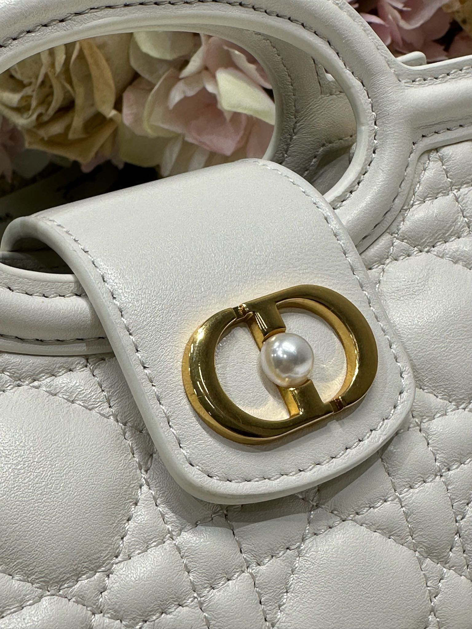 Dior Jolie Top Handle 迷你链条手袋「白色」
这款 Dior Jolie Top Handle 迷你链条手袋是二零二六早春成衣系列新品，呈现出优雅精致的设计。采用奶白色羊皮革精心制作，饰以藤格纹，翻盖点缀以金色饰面金属 CD 标志和白色树脂珠饰。内设一个隔层，可收纳各种日常用品。搭配双顶部手柄和可调节、可拆卸 CD 链条肩带，肩带由皮革带和 CD 链环组成，饰以白色树脂珠饰，可舒适手提、肩背或斜挎，可与日常或晚装造型搭配。p570
磁性翻盖开合正面饰以 CD 扣环和白色树脂珠饰
1 个隔层
双顶部皮革手柄
可调节、可拆卸的链条饰以树脂珠饰和皮革带

型号：3123
尺寸：18.5 x 13 x 8.5 厘米（长 x 高 x 宽）
可收纳 1 部手机、1 个卡夹、太阳眼镜和唇膏