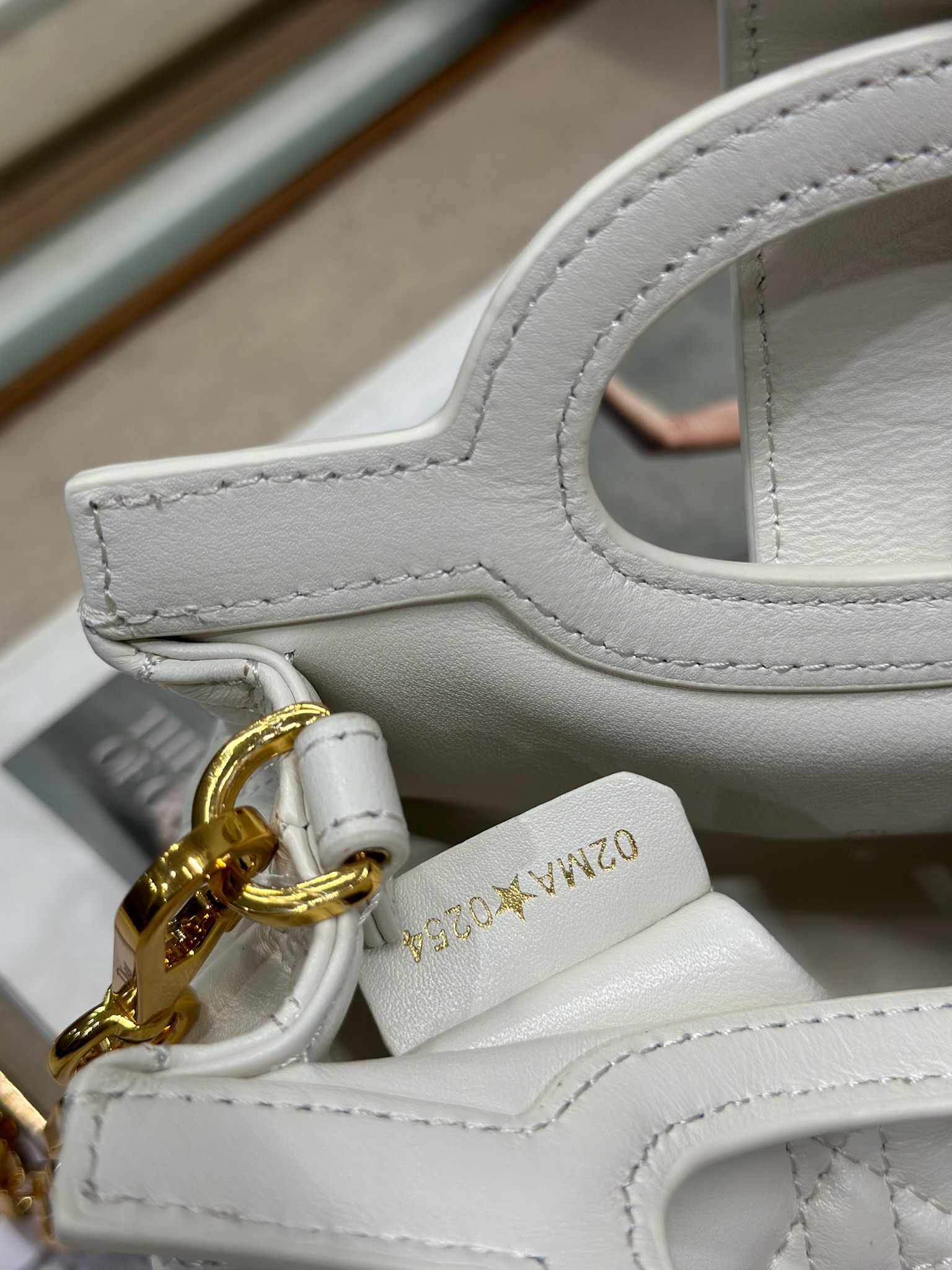 Dior Jolie Top Handle 迷你链条手袋「白色」
这款 Dior Jolie Top Handle 迷你链条手袋是二零二六早春成衣系列新品，呈现出优雅精致的设计。采用奶白色羊皮革精心制作，饰以藤格纹，翻盖点缀以金色饰面金属 CD 标志和白色树脂珠饰。内设一个隔层，可收纳各种日常用品。搭配双顶部手柄和可调节、可拆卸 CD 链条肩带，肩带由皮革带和 CD 链环组成，饰以白色树脂珠饰，可舒适手提、肩背或斜挎，可与日常或晚装造型搭配。p570
磁性翻盖开合正面饰以 CD 扣环和白色树脂珠饰
1 个隔层
双顶部皮革手柄
可调节、可拆卸的链条饰以树脂珠饰和皮革带

型号：3123
尺寸：18.5 x 13 x 8.5 厘米（长 x 高 x 宽）
可收纳 1 部手机、1 个卡夹、太阳眼镜和唇膏