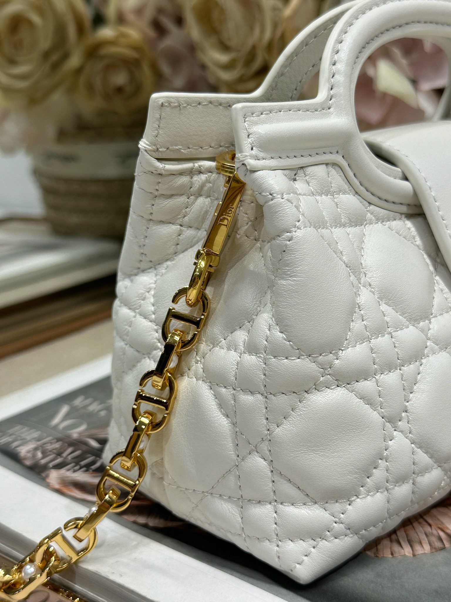 Dior Jolie Top Handle 迷你链条手袋「白色」
这款 Dior Jolie Top Handle 迷你链条手袋是二零二六早春成衣系列新品，呈现出优雅精致的设计。采用奶白色羊皮革精心制作，饰以藤格纹，翻盖点缀以金色饰面金属 CD 标志和白色树脂珠饰。内设一个隔层，可收纳各种日常用品。搭配双顶部手柄和可调节、可拆卸 CD 链条肩带，肩带由皮革带和 CD 链环组成，饰以白色树脂珠饰，可舒适手提、肩背或斜挎，可与日常或晚装造型搭配。p570
磁性翻盖开合正面饰以 CD 扣环和白色树脂珠饰
1 个隔层
双顶部皮革手柄
可调节、可拆卸的链条饰以树脂珠饰和皮革带

型号：3123
尺寸：18.5 x 13 x 8.5 厘米（长 x 高 x 宽）
可收纳 1 部手机、1 个卡夹、太阳眼镜和唇膏