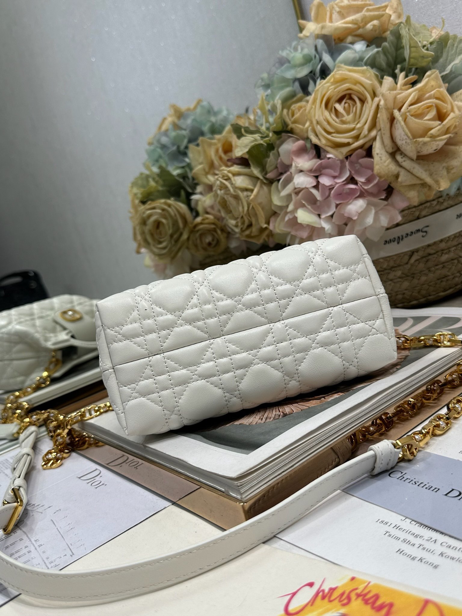 Dior Jolie Top Handle 迷你链条手袋「白色」
这款 Dior Jolie Top Handle 迷你链条手袋是二零二六早春成衣系列新品，呈现出优雅精致的设计。采用奶白色羊皮革精心制作，饰以藤格纹，翻盖点缀以金色饰面金属 CD 标志和白色树脂珠饰。内设一个隔层，可收纳各种日常用品。搭配双顶部手柄和可调节、可拆卸 CD 链条肩带，肩带由皮革带和 CD 链环组成，饰以白色树脂珠饰，可舒适手提、肩背或斜挎，可与日常或晚装造型搭配。p570
磁性翻盖开合正面饰以 CD 扣环和白色树脂珠饰
1 个隔层
双顶部皮革手柄
可调节、可拆卸的链条饰以树脂珠饰和皮革带

型号：3123
尺寸：18.5 x 13 x 8.5 厘米（长 x 高 x 宽）
可收纳 1 部手机、1 个卡夹、太阳眼镜和唇膏