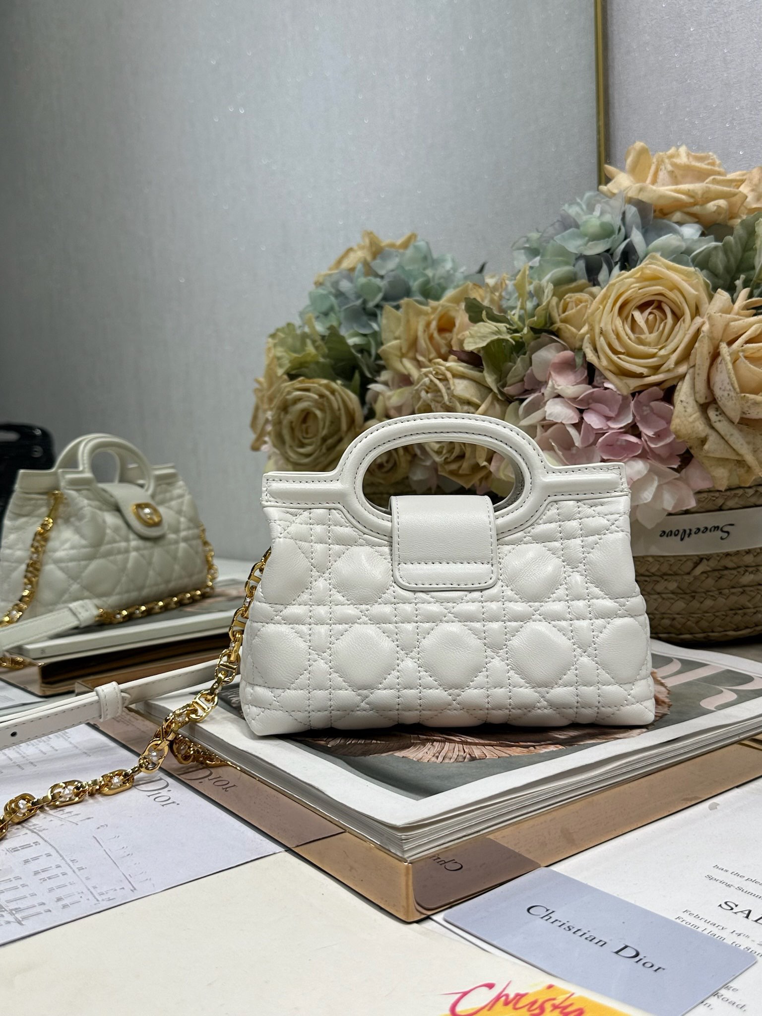 Dior Jolie Top Handle 迷你链条手袋「白色」
这款 Dior Jolie Top Handle 迷你链条手袋是二零二六早春成衣系列新品，呈现出优雅精致的设计。采用奶白色羊皮革精心制作，饰以藤格纹，翻盖点缀以金色饰面金属 CD 标志和白色树脂珠饰。内设一个隔层，可收纳各种日常用品。搭配双顶部手柄和可调节、可拆卸 CD 链条肩带，肩带由皮革带和 CD 链环组成，饰以白色树脂珠饰，可舒适手提、肩背或斜挎，可与日常或晚装造型搭配。p570
磁性翻盖开合正面饰以 CD 扣环和白色树脂珠饰
1 个隔层
双顶部皮革手柄
可调节、可拆卸的链条饰以树脂珠饰和皮革带

型号：3123
尺寸：18.5 x 13 x 8.5 厘米（长 x 高 x 宽）
可收纳 1 部手机、1 个卡夹、太阳眼镜和唇膏
