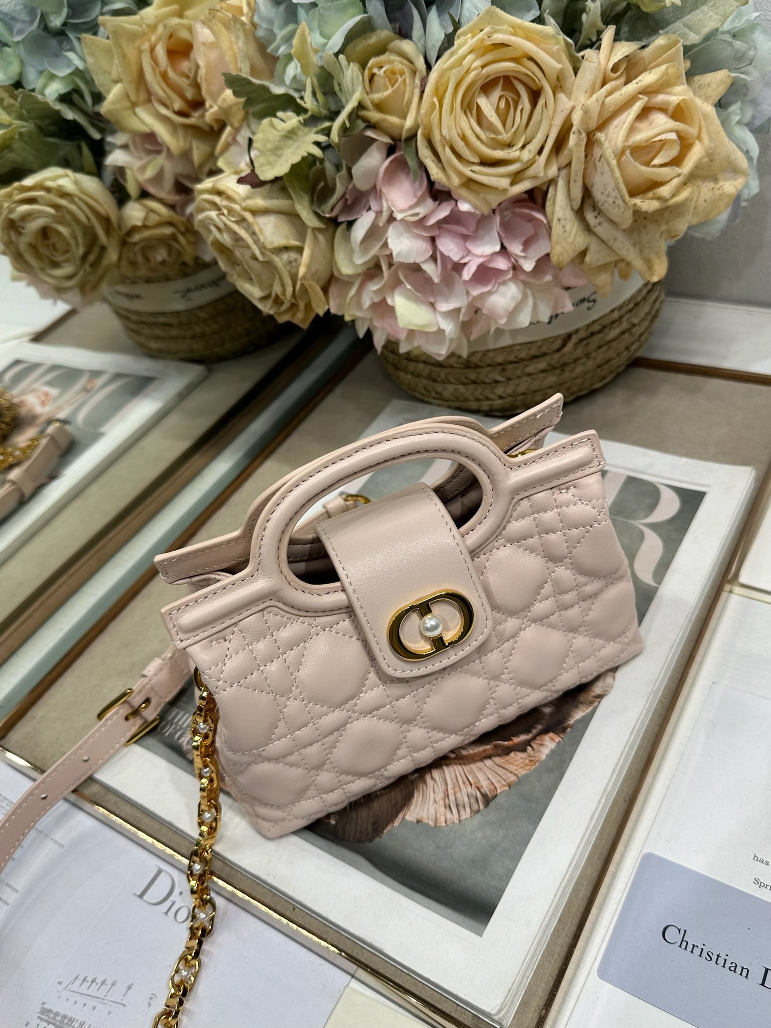 Dior Jolie Top Handle 迷你链条手袋「粉色」
这款 Dior Jolie Top Handle 迷你链条手袋是二零二六早春成衣系列新品，呈现出优雅精致的设计。采用粉色羊皮革精心制作，饰以藤格纹，翻盖点缀以金色饰面金属 CD 标志和白色树脂珠饰。内设一个隔层，可收纳各种日常用品。搭配双顶部手柄和可调节、可拆卸 CD 链条肩带，肩带由皮革带和 CD 链环组成，饰以白色树脂珠饰，可舒适手提、肩背或斜挎，可与日常或晚装造型搭配。p570
磁性翻盖开合正面饰以 CD 扣环和白色树脂珠饰
1 个隔层
双顶部皮革手柄
可调节、可拆卸的链条饰以树脂珠饰和皮革带

型号：3123
尺寸：18.5 x 13 x 8.5 厘米（长 x 高 x 宽）
可收纳 1 部手机、1 个卡夹、太阳眼镜和唇膏