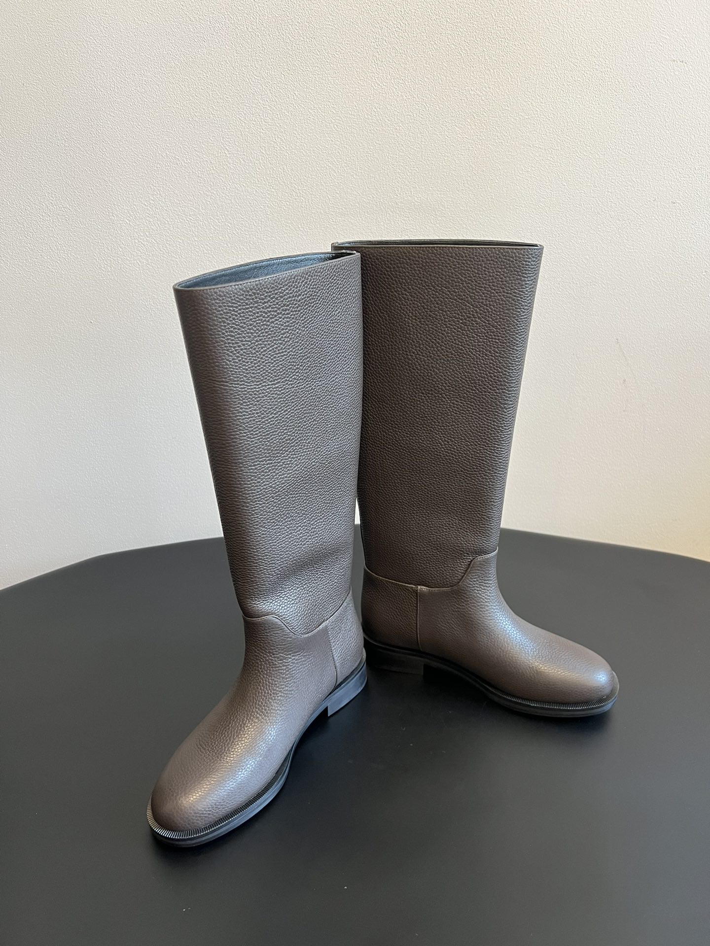 Khaite 25ss 荔枝纹皮革长靴采用荔枝纹皮革材质，触感细腻且质感高级，呈现出深灰色和棕灰色两种低