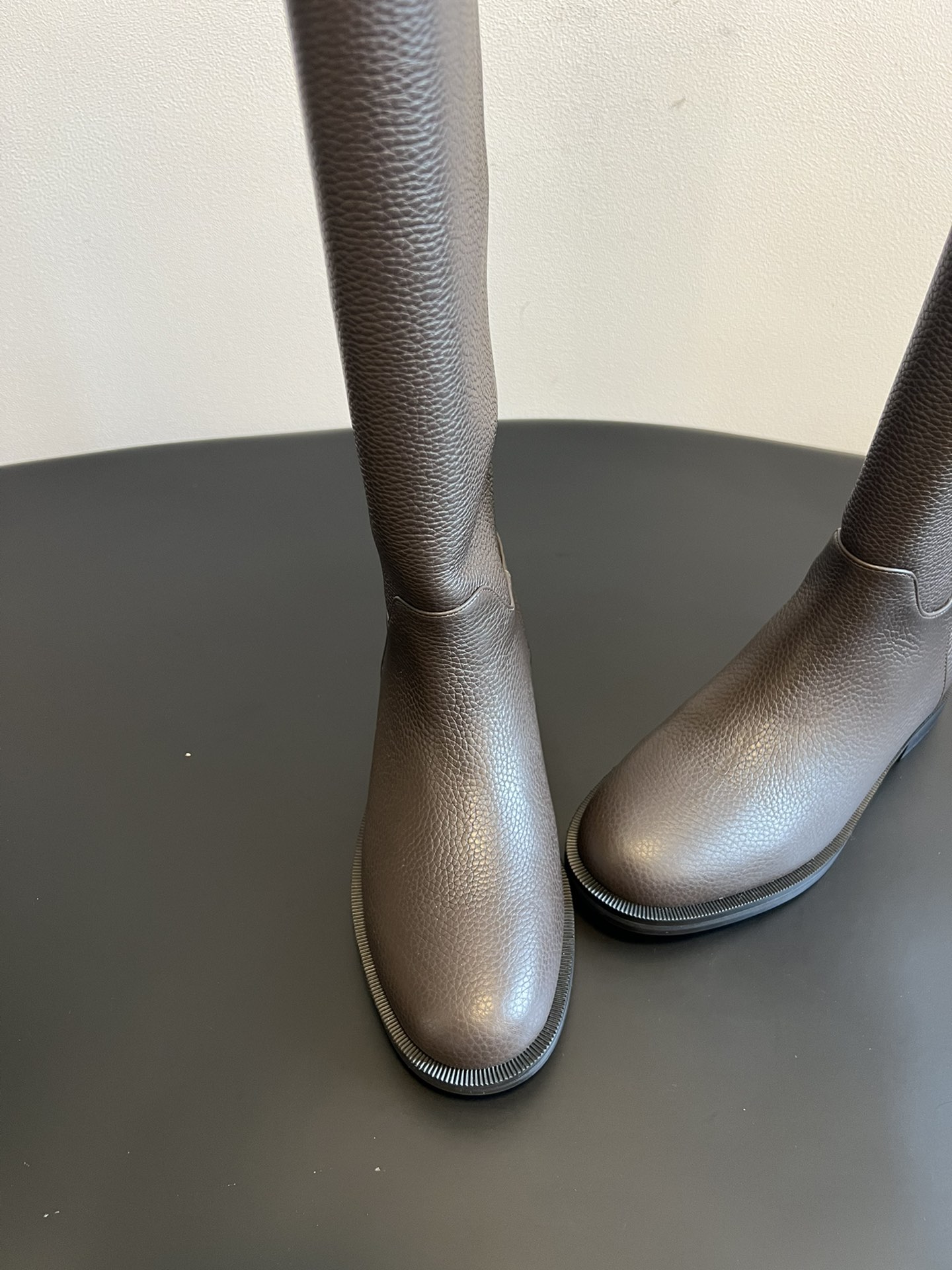 Khaite 25ss 荔枝纹皮革长靴采用荔枝纹皮革材质，触感细腻且质感高级，呈现出深灰色和棕灰色两种低