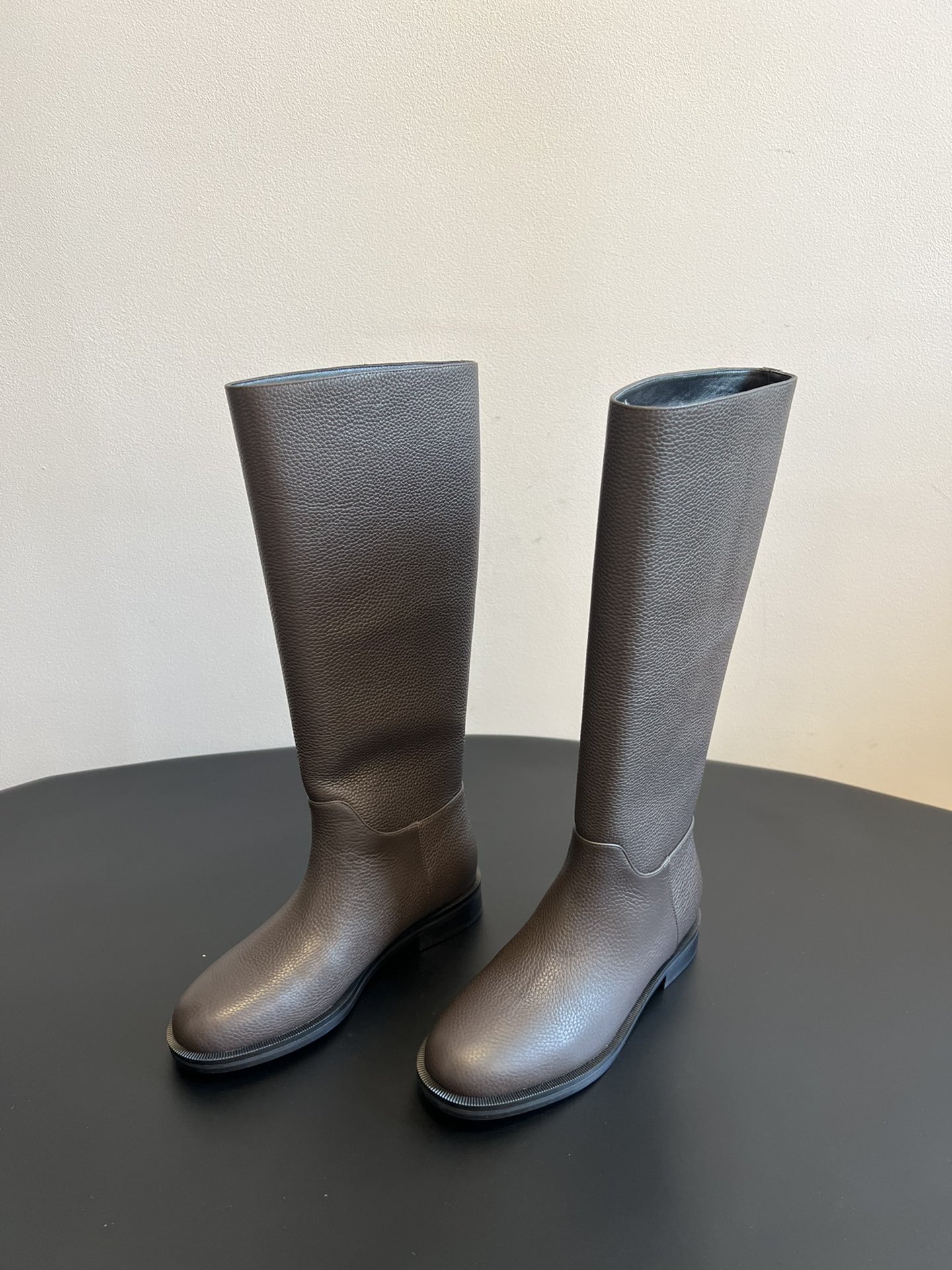 Khaite 25ss 荔枝纹皮革长靴采用荔枝纹皮革材质，触感细腻且质感高级，呈现出深灰色和棕灰色两种低