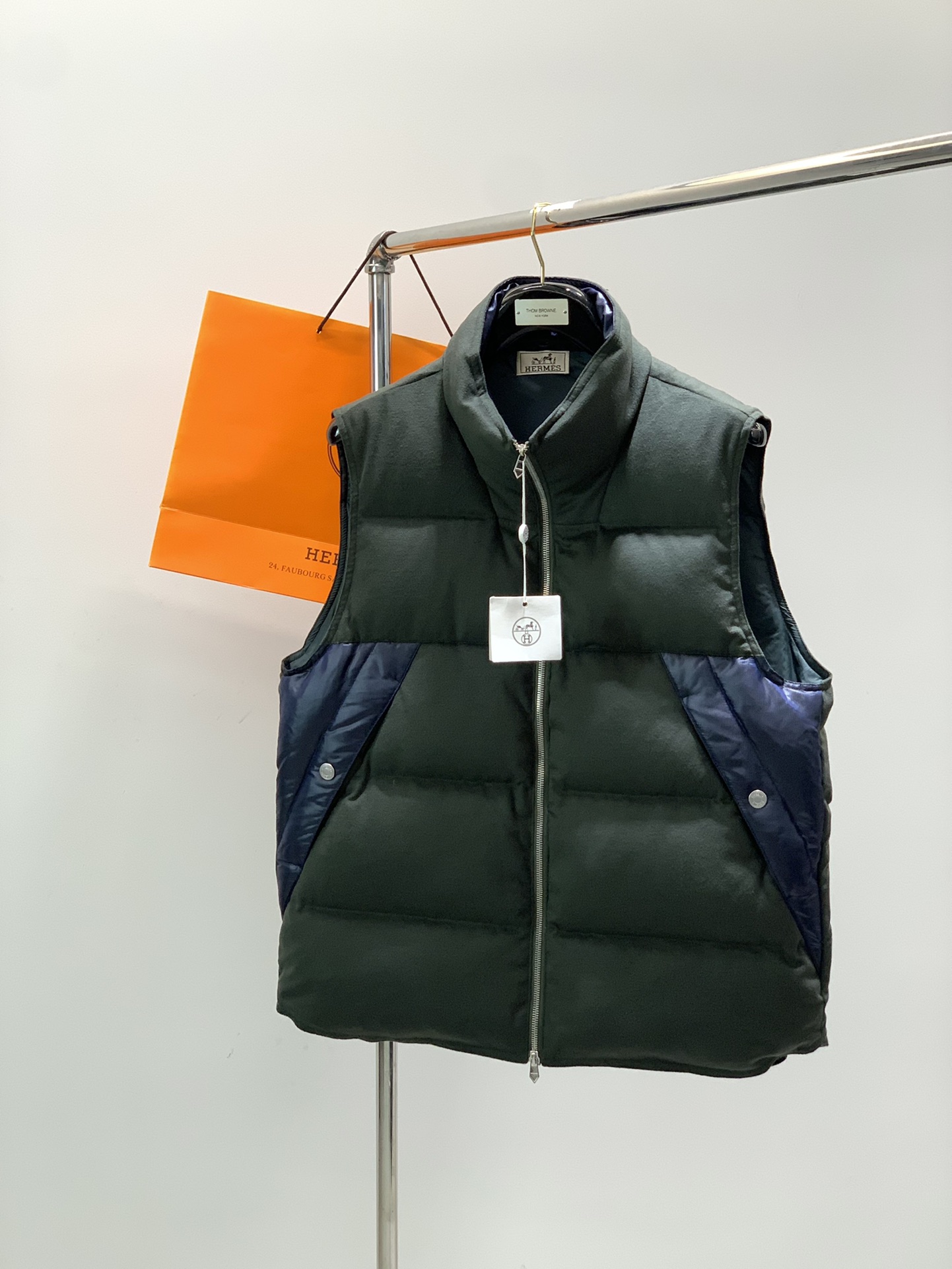 NO:567337,, Hermès Australian superfine wool spliced Toray technical fiber white goose down filled funnel collar down vest About style and design  Big H's poster style, high-end men's wear series, draping deconstruction and diverse mix-and-match are the standout points of this group of styles. The main body is made of ultra-fine Australian wool combined with farran technology, and the most luxurious woolen fabric is used to subvert the inherent configuration of down items. The 'nobility' visible to the naked eye contributes to the high-luxury tone of the vest. It can be hidden and closed.  The hat body and the elastic hem with three-dimensional built-in and extended design, including the placket frame, inner hanging surface, and pocket outer frame are all made of Japanese Toray's technical fiber, woolen material VS nylon fiber, with multiple collisions in texture and shape, thus contributing to the overall draped deconstruction effect. Black all  Black is relatively restrained, with dark green contrasting with navy blue, giving it a bit of visual impact.   The design of the hem is the soul. It has a three-dimensional built-in hem design. The extra length compared to the body, combined with the turned-out hat body and the inlaid strip of the placket, creates the effect of a fake two-piece. It is like layering a baseball collar down jacket on top of a hooded jacket.  It has an immediate visual effect. The nylon splicing part of the hem is filled with a warm cotton layer, which has a thickness gap with the body, and deepens the three-dimensional sense of structure. The curved raglan sleeves and the multi-bag design with minimalist lines on the body make the overall look young and fashionable.  About fabrics and craftsmanship   The main body fabric is 20 wool, 20 viscose, 57 polyester, 3 spandex, the splicing part is 64 polyester, 36 nylon, the lining is nylon, and the lining is filled with 90 white goose down and 10 feathers. Australian ultra-fine wool is woven into high quality through flannel technology.  The dense but soft and silky thin fabric has a colorful texture and is easy to care for, and it is visible to the naked eye. The splicing part comes from Toray's technical fiber, with a dark herringbone texture, a high-end color, a satin texture, windproof, waterproof and tear-proof, and extremely functional.  Size 48, 50, 52, 54 Size chart 48 Bust 114 Shoulder width 44 Length 70. 50 Bust 118 Shoulder width 45 Length 71.52 Bust 122 Shoulder width 46 Length 72.54 Bust 126 Shoulder width 47 Length 73.,,hermes,jackets &   coats,down jacket,hats,alexander wang19860909,爱马仕 澳洲超细羊毛拼接东丽科技纤维白鹅绒填充漏斗领羽绒马甲 关于款式及设计 大H的海报款,高级男装系列,立裁解构和多元混搭是本组款的脱颖点,大身主体是超细澳毛结合法拉绒工艺,用顶奢的毛呢面料来颠覆羽绒单品的固有配置,肉眼可见的“显贵”,助力了马甲的高奢调性.而可隐形收纳的帽体以及立体内置并加长设计的松紧下摆,包括门襟边框,内里挂面,以及口袋外框均采用了日本东丽的科技纤维,羊毛呢料VS尼龙纤维,在质感和形态上多重碰撞,从而助力了整体的立裁解构效果.黑色all black相对内敛,墨绿撞藏蓝,视觉冲击感到位. 下摆的设计是灵魂,做了一个立体内置的衣摆设计,比大身多出来的那一截,与外翻出来的帽体,门襟的镶嵌条,组合出了假两件的效果,有在连帽夹克基础上叠穿棒球领羽绒服的即视效果.下摆的尼龙拼接部分内里填充了保暖棉层,与大身有厚薄落差,并加深了结构上的立体层次感.弧度立裁的插肩袖,大身上极简线条的多袋设计,整体偏年轻且时髦. 关于面料及工艺 大身面料20羊毛20粘胶纤维57聚酯纤维3氨纶,拼接部分64聚酯纤维36锦纶,里布锦纶,内里填充90白鹅绒10羽毛.澳洲超细的羊毛,经法兰绒工艺,织成高密度但柔软丝滑的薄呢料,质感出彩且易打理,肉眼可见的显贵.拼接部分来自东丽的科技纤维,鱼骨纹的暗纹肌理,色泽高级,有缎面质感,防风防水防撕裂,机能性极强. 尺码48,50,52,54 尺码表48胸围114肩宽44衣长70.  50胸围118肩宽45衣长71.52胸围122肩宽46衣长72.54胸围126肩宽47衣长73.,,hermes,jackets & coats,down jacket,hats,alexander wang,Men's clothing