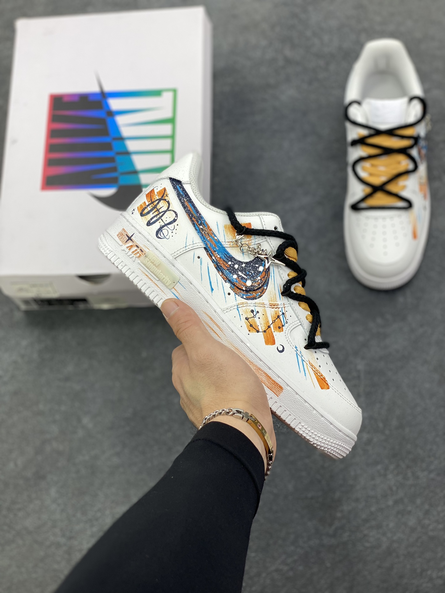 手绘涂鸦“天蝎座”十二星座系列 Nike Air Force 1 “Scorpio”空军一号定制板鞋 纯白鞋身化作星穹画布，泼墨般的蓝橙笔触勾勒天蝎座的神秘轮廓，星轨纹路在鞋侧肆意延展，双色系鞋带缠绕出不羁风格，专属星座挂饰更添细节温度。它不止是一双鞋，更是天蝎特质的具象表达——冷冽中藏着热烈，小众里透着锋芒，将星座文化、手绘艺术与街头潮流熔于一炉，让每一步都似在星际间留下独特轨迹 货号：星座10241122 尺码：36 36.5 37.5 38 38.5 39 40 40.5 41 42 42.5 43 44 44.5 45-选品中心