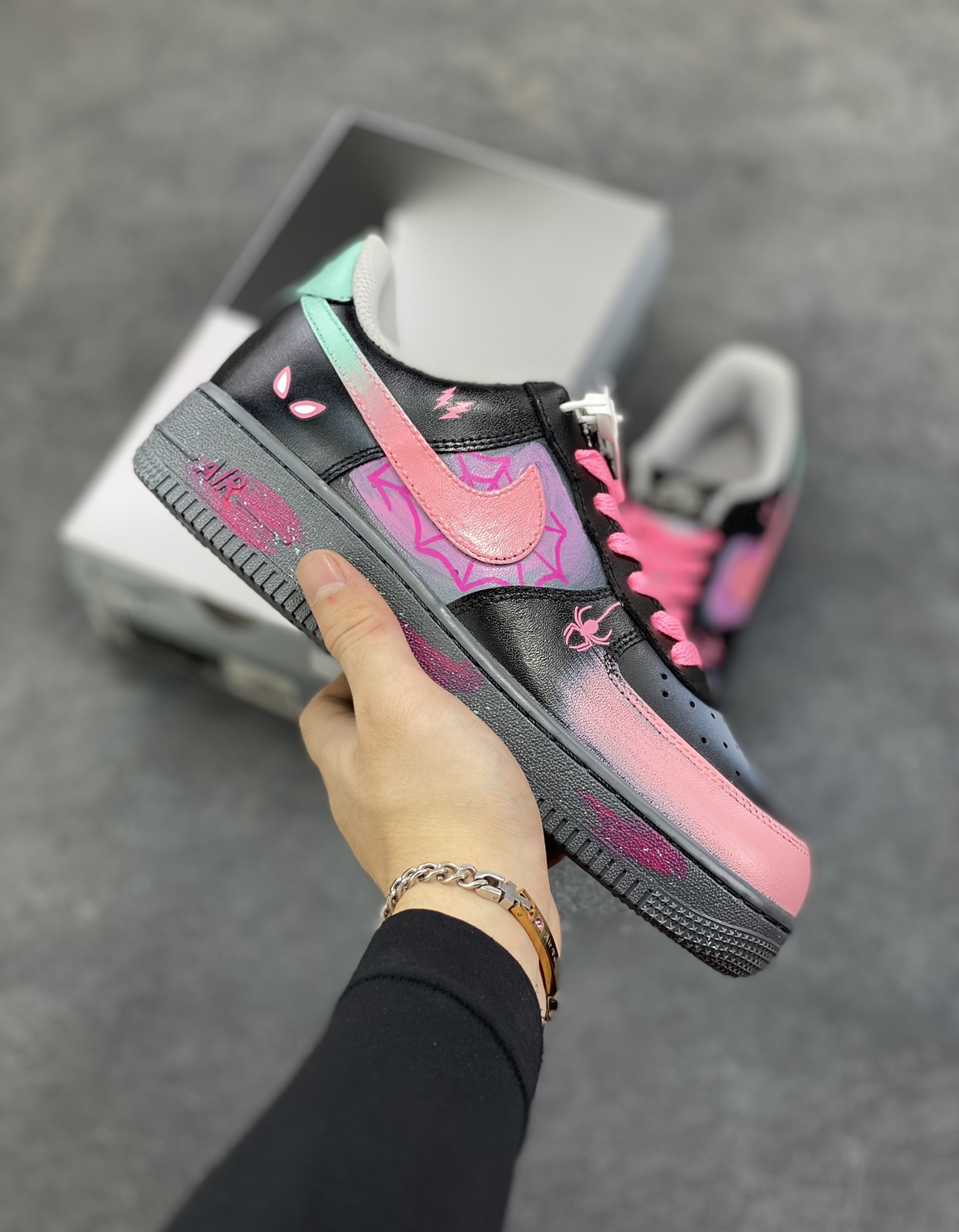 手绘涂鸦“粉电蛛影”Nike Air Force 1 “Pink electric spider shadow”空军一号定制板鞋 粉嫩的Swoosh与蛛网图案交缠，似是蜘蛛侠宇宙里迸发出的霓虹脉络；黑色鞋身点缀的闪电符号、神秘蛛眼，又为其注入几分街头的酷感张力。鞋头渐变的粉紫、中底泼墨般的彩点，在灰调基底上晕染出艺术感，每一处细节都像是潮酷青年的自我宣言——既怀揣着对英雄世界的绮梦，又绝不妥协于平庸的街头风格 货号：YD2425-011 尺码：36 36.5 37.5 38 38.5 39 40 40.5 41 42 42.5 43 44 44.5 45-选品中心